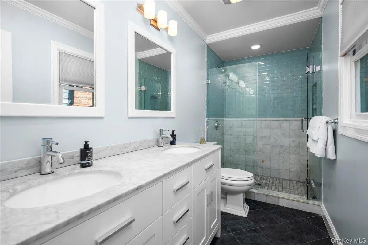 Renovated private bath features a double marble vanity and glass-enclosed shower with marble and blue tile detailing for a fresh, polished finish. Renovated private bath features a double marble vanity and glass-enclosed shower with marble and blue tile detailing for a fresh, polished finish.