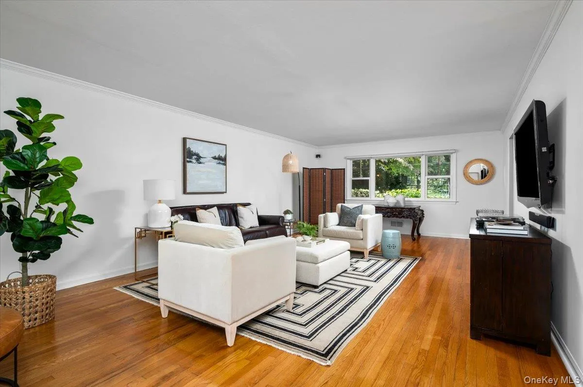 Expansive living room with hardwood floors, crown molding and oversized windows provides generous space for conversation, relaxing and entertaining. Expansive living room with hardwood floors, crown molding and oversized windows provides generous space for conversation, relaxing and entertaining.