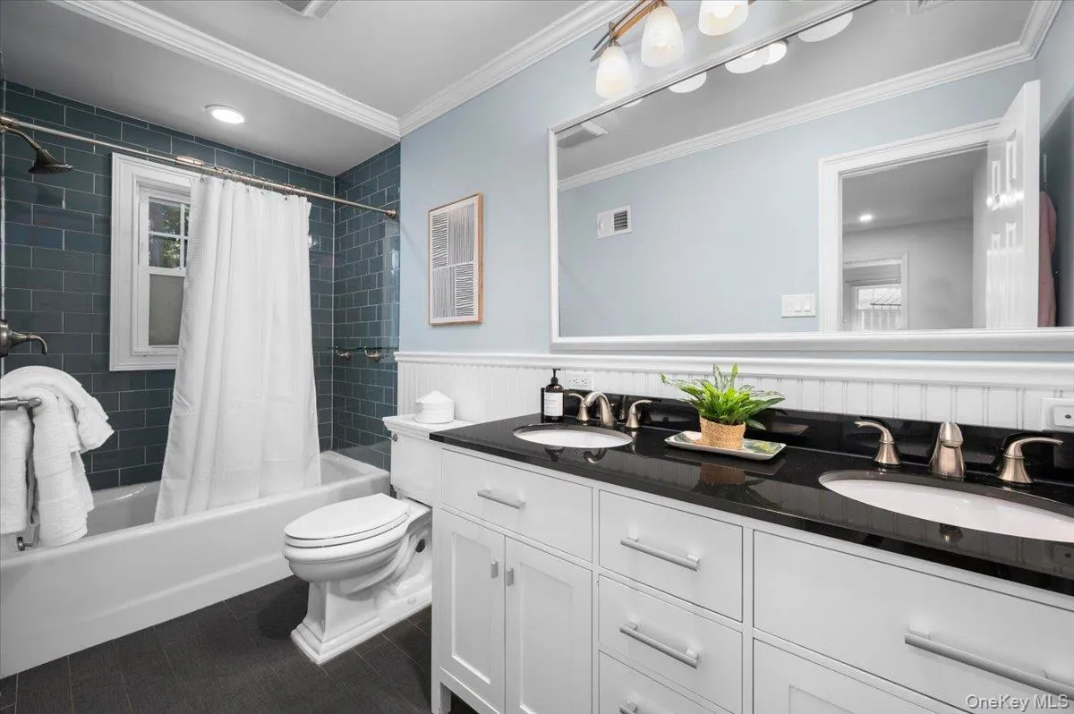 Updated hall bath offers a double-sink vanity, expansive mirror and tub/shower with rich blue tile—valuable functionality on the bedroom level. Updated hall bath offers a double-sink vanity, expansive mirror and tub/shower with rich blue tile—valuable functionality on the bedroom level.