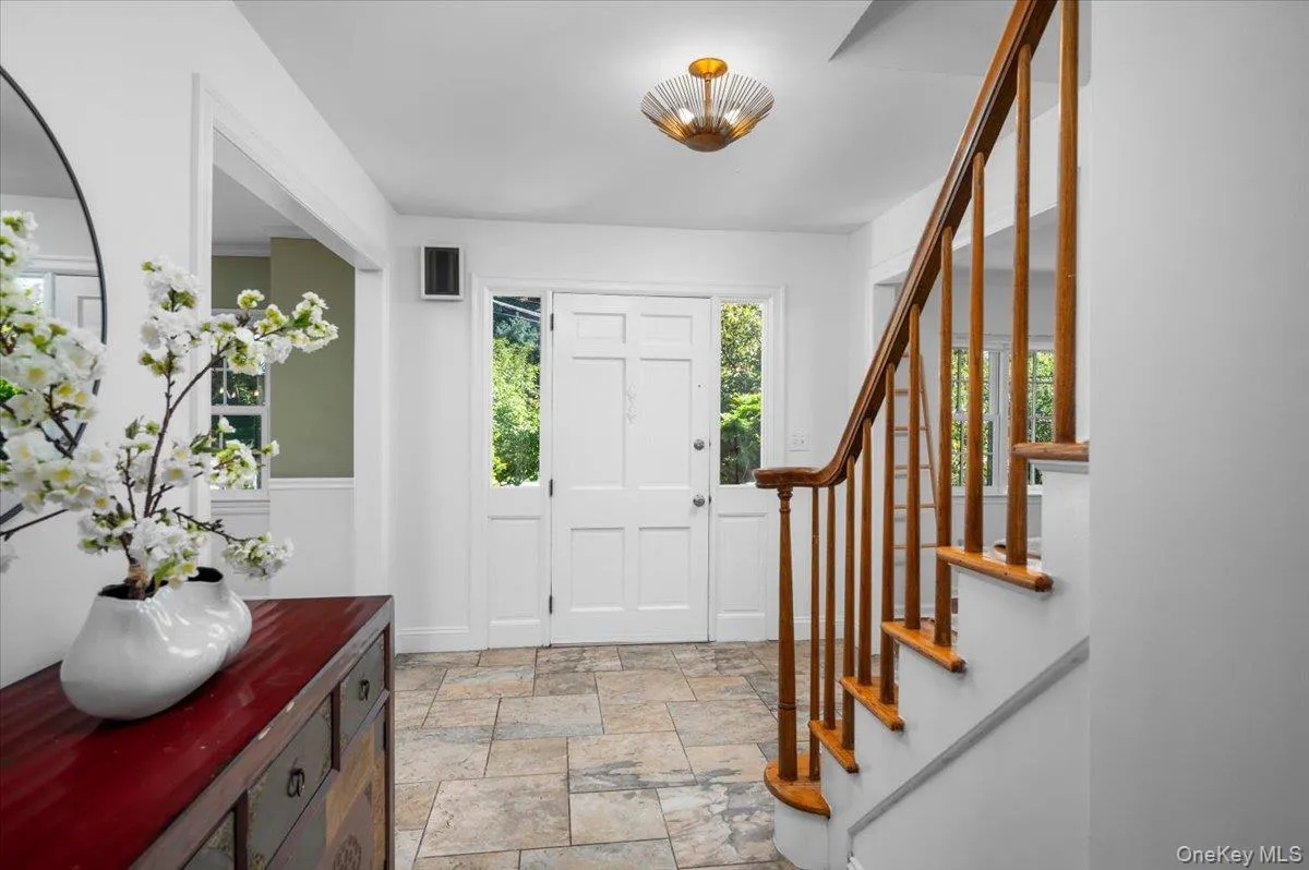 The bright center-hall foyer features stone tile flooring, classic millwork and a warm wood staircase, introducing the home’s easy, well-connected floor plan. The bright center-hall foyer features stone tile flooring, classic millwork and a warm wood staircase, introducing the home’s easy, well-connected floor plan.