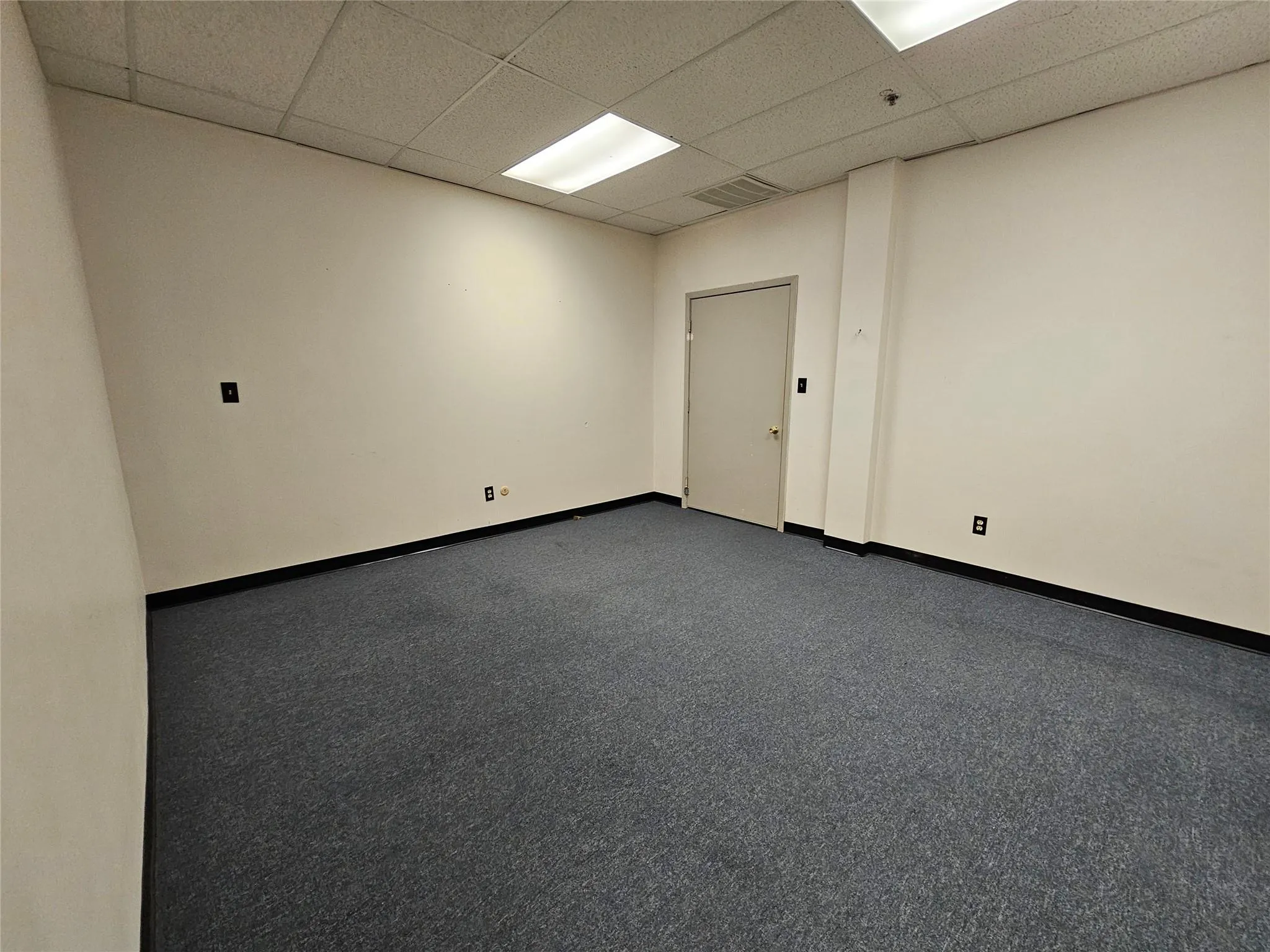Spare room with a drop ceiling, baseboards, and dark carpet Spare room with a drop ceiling, baseboards, and dark carpet