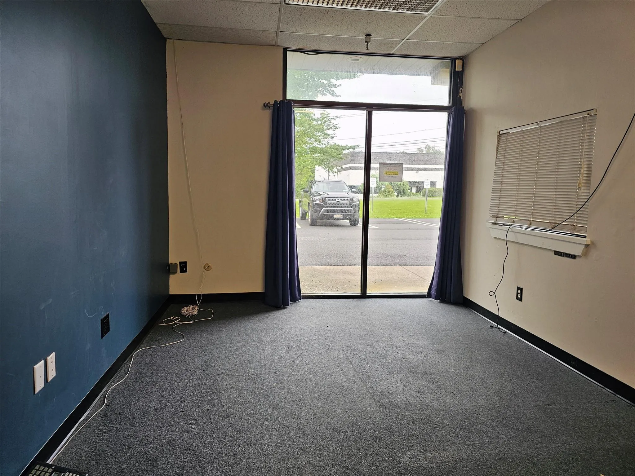 Empty room featuring floor to ceiling windows, a paneled ceiling, carpet, and baseboards Empty room featuring floor to ceiling windows, a paneled ceiling, carpet, and baseboards
