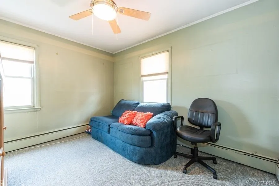 Living area featuring a baseboard heating unit, carpet, crown molding, and a ceiling fan Living area featuring a baseboard heating unit, carpet, crown molding, and a ceiling fan