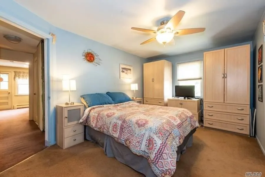 Carpeted bedroom with baseboard heating and a ceiling fan Carpeted bedroom with baseboard heating and a ceiling fan