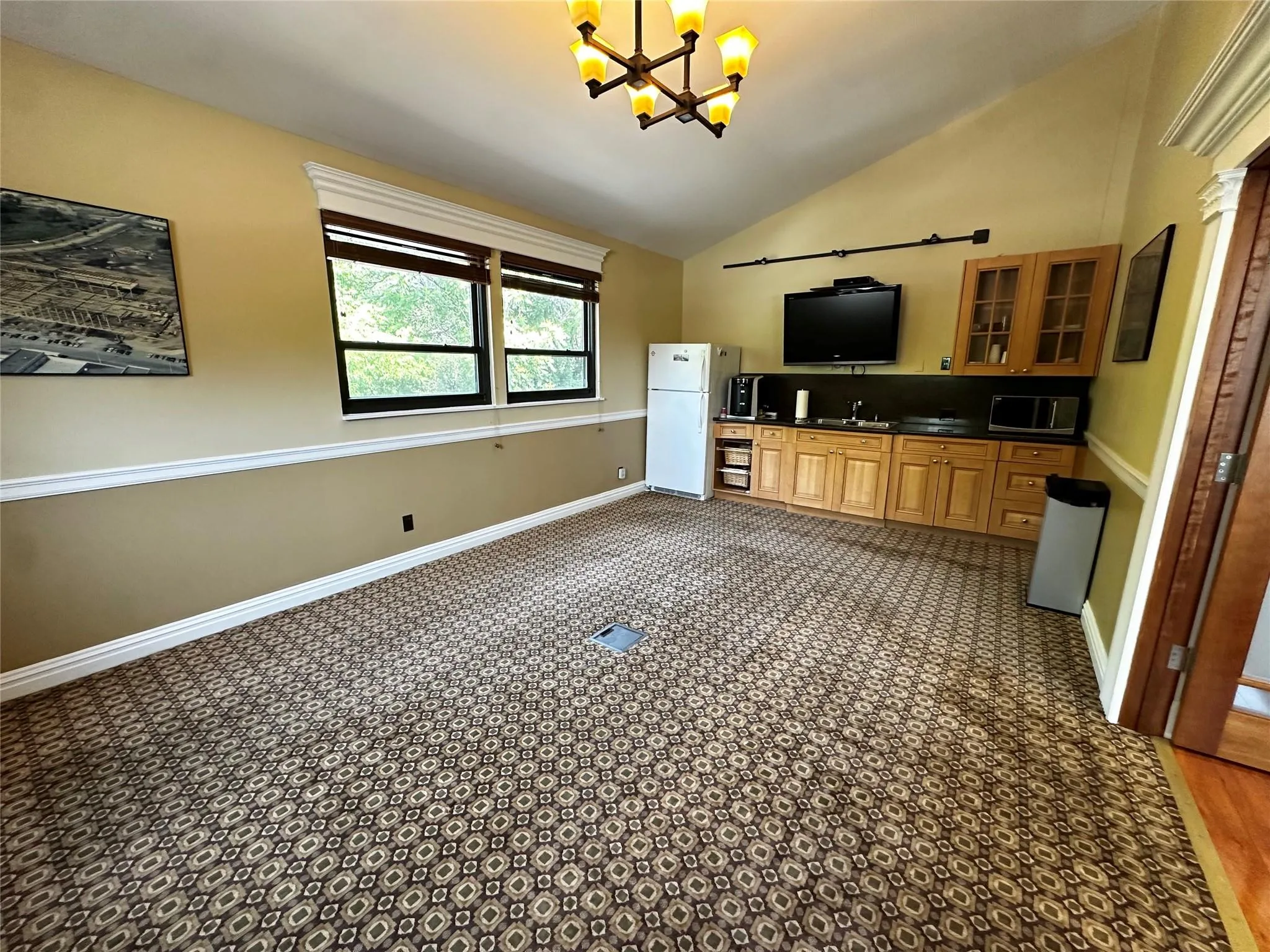 Kitchen featuring freestanding refrigerator, a chandelier, dark countertops, glass insert cabinets, and high vaulted ceiling Kitchen featuring freestanding refrigerator, a chandelier, dark countertops, glass insert cabinets, and high vaulted ceiling