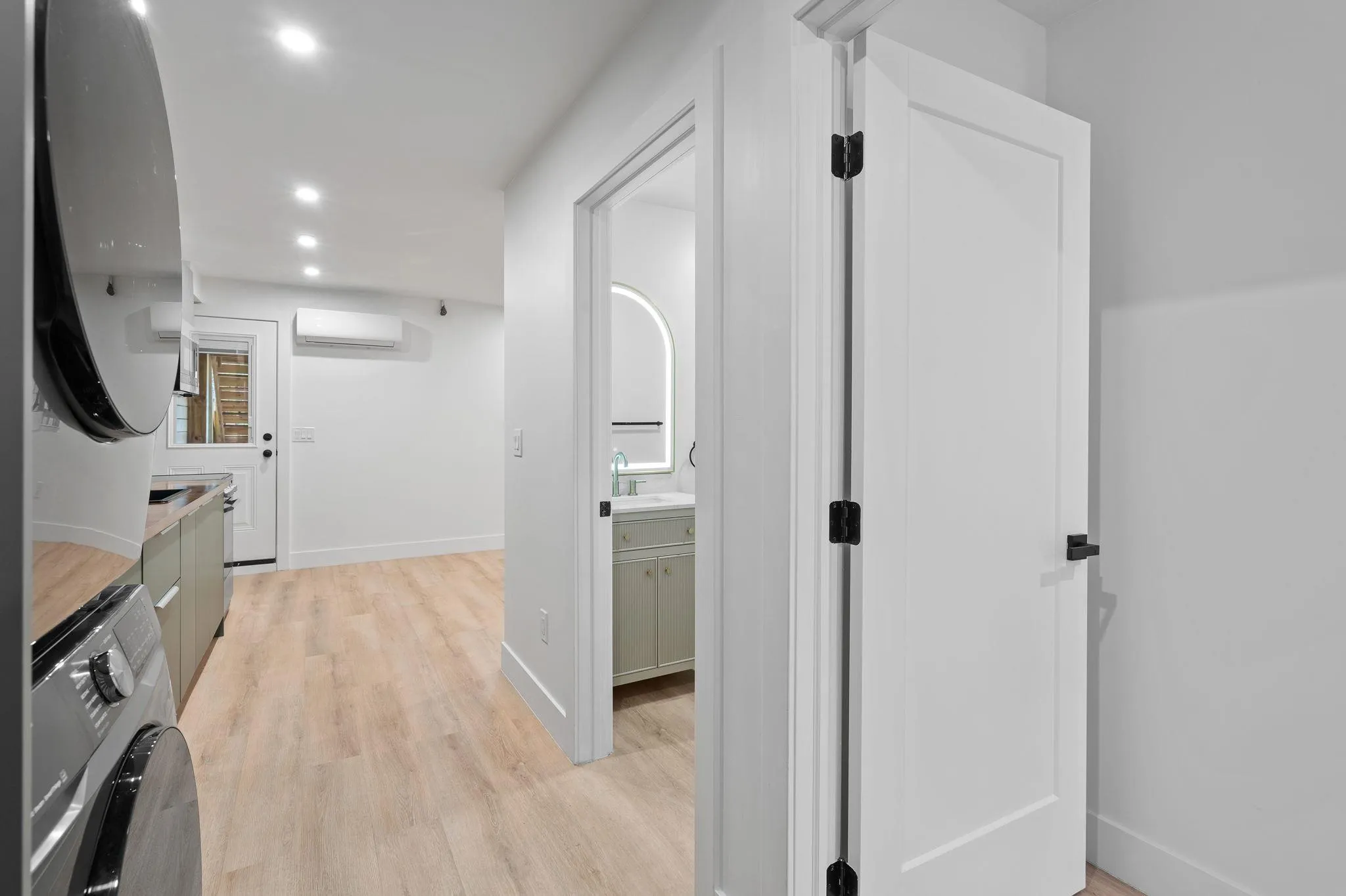 Hallway with light hardwood / wood-style floors, sink, washer / clothes dryer, and a wall mounted AC Hallway with light hardwood / wood-style floors, sink, washer / clothes dryer, and a wall mounted AC