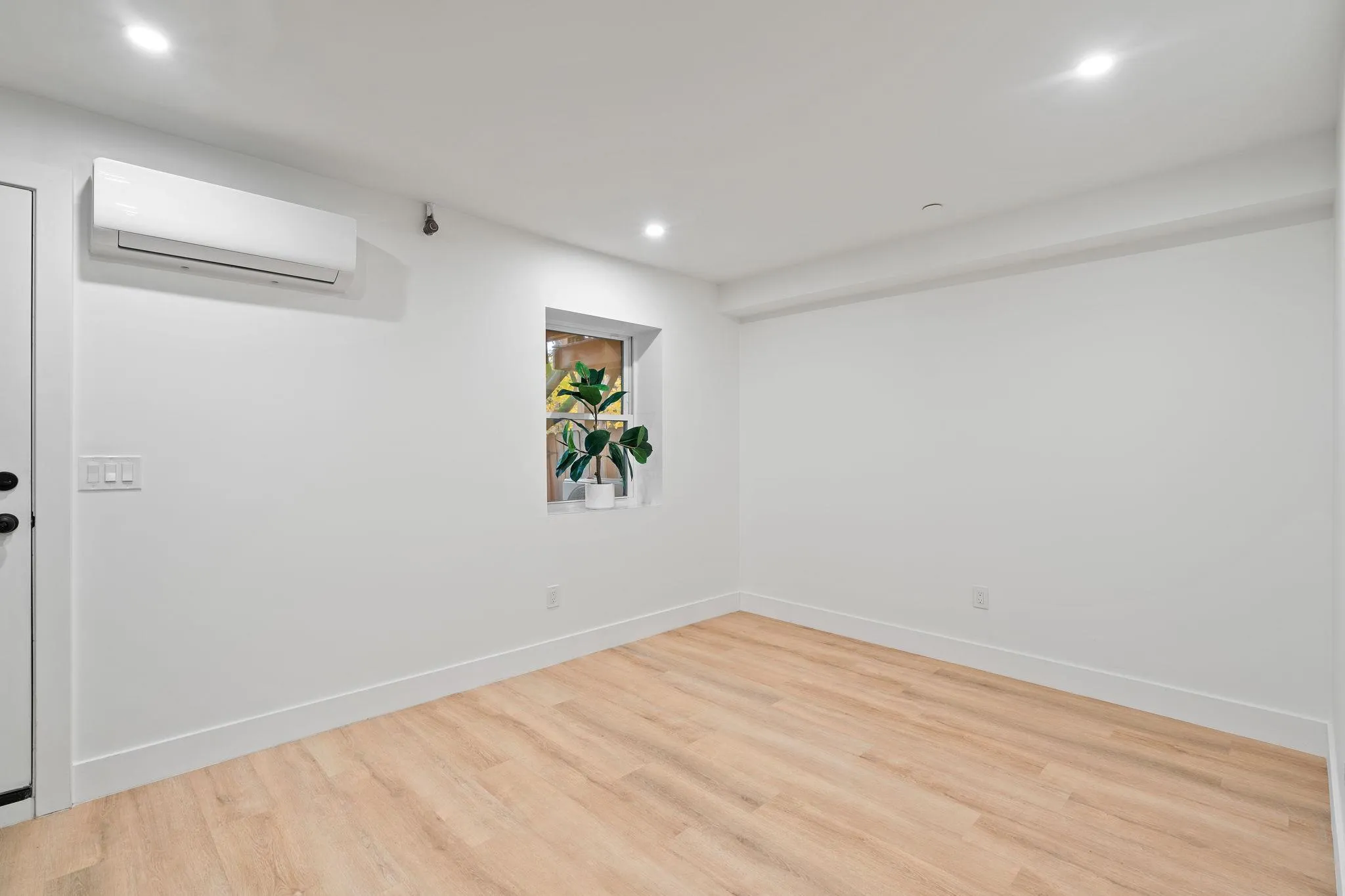 Unfurnished room with a wall unit AC and hardwood / wood-style flooring Unfurnished room with a wall unit AC and hardwood / wood-style flooring