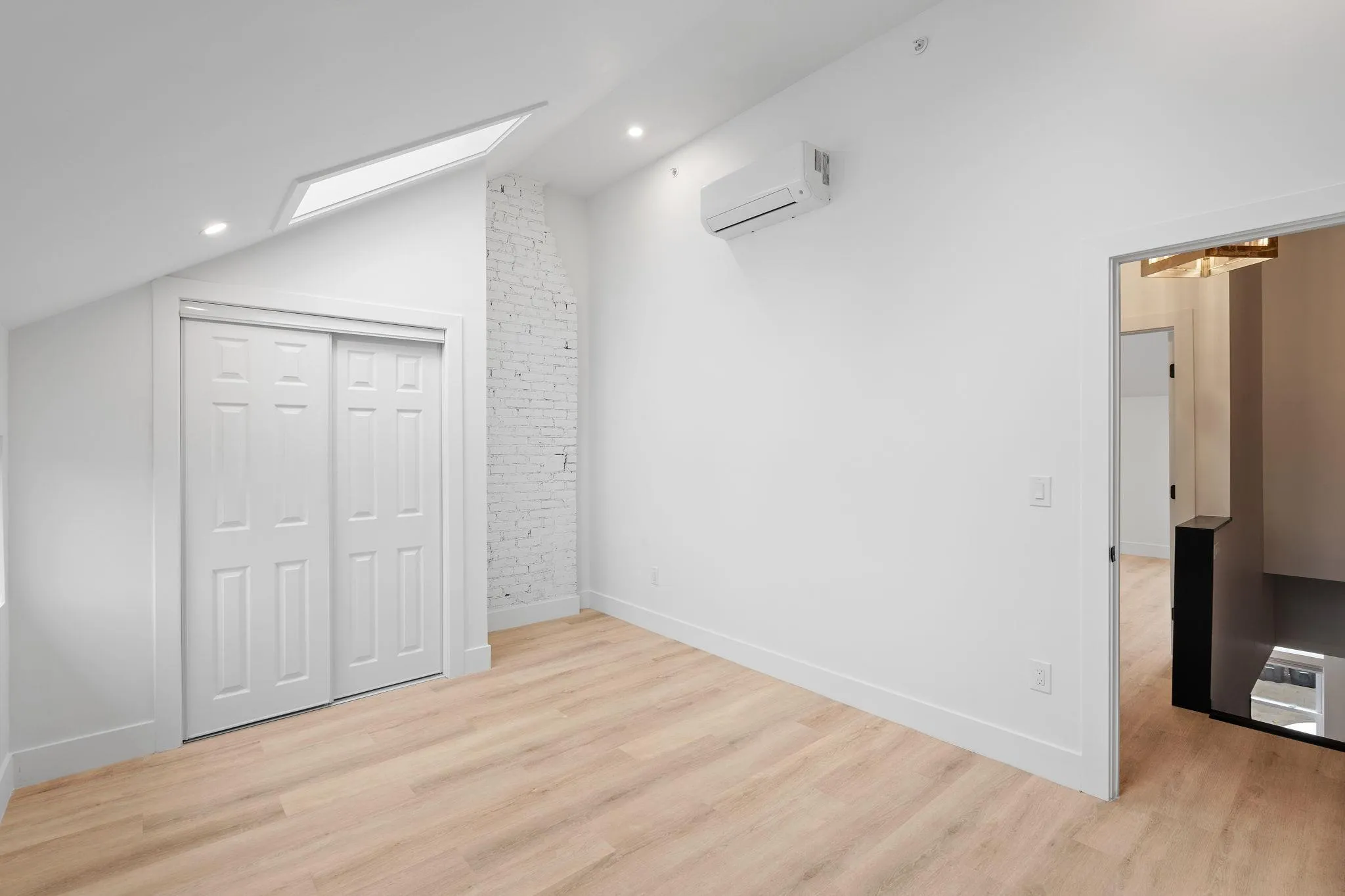 Unfurnished bedroom featuring light wood-type flooring, an AC wall unit, a closet, and lofted ceiling Unfurnished bedroom featuring light wood-type flooring, an AC wall unit, a closet, and lofted ceiling