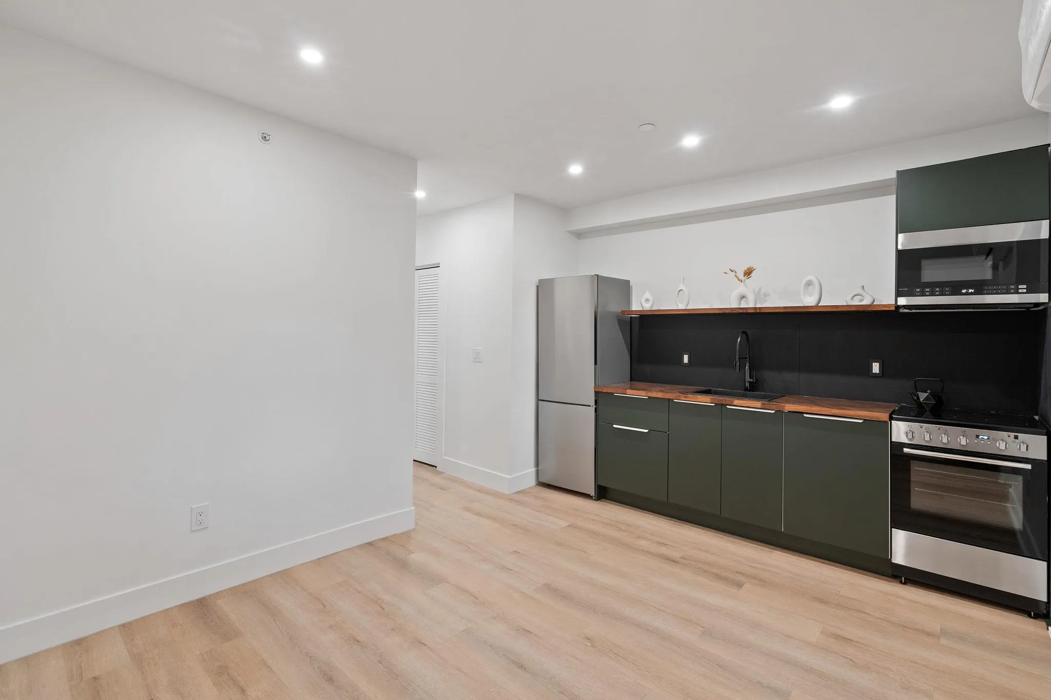 Kitchen with appliances with stainless steel finishes, light hardwood / wood-style flooring, green cabinets, and sink Kitchen with appliances with stainless steel finishes, light hardwood / wood-style flooring, green cabinets, and sink
