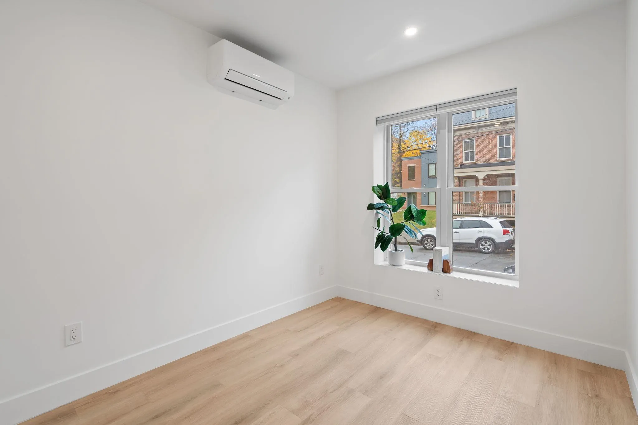 Empty room with light hardwood / wood-style floors and a wall mounted air conditioner Empty room with light hardwood / wood-style floors and a wall mounted air conditioner