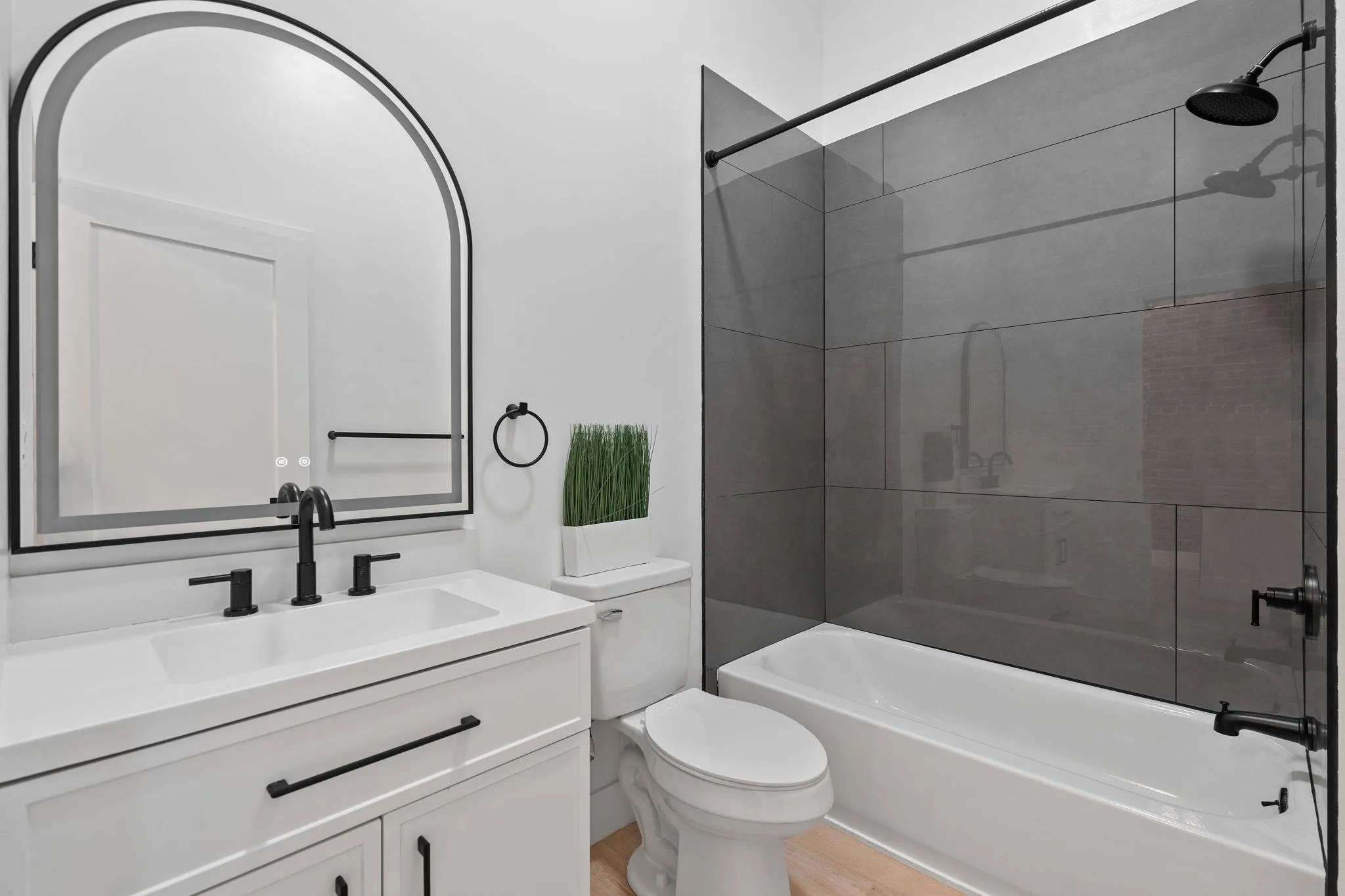 Full bathroom featuring vanity, wood-type flooring, tiled shower / bath combo, and toilet Full bathroom featuring vanity, wood-type flooring, tiled shower / bath combo, and toilet