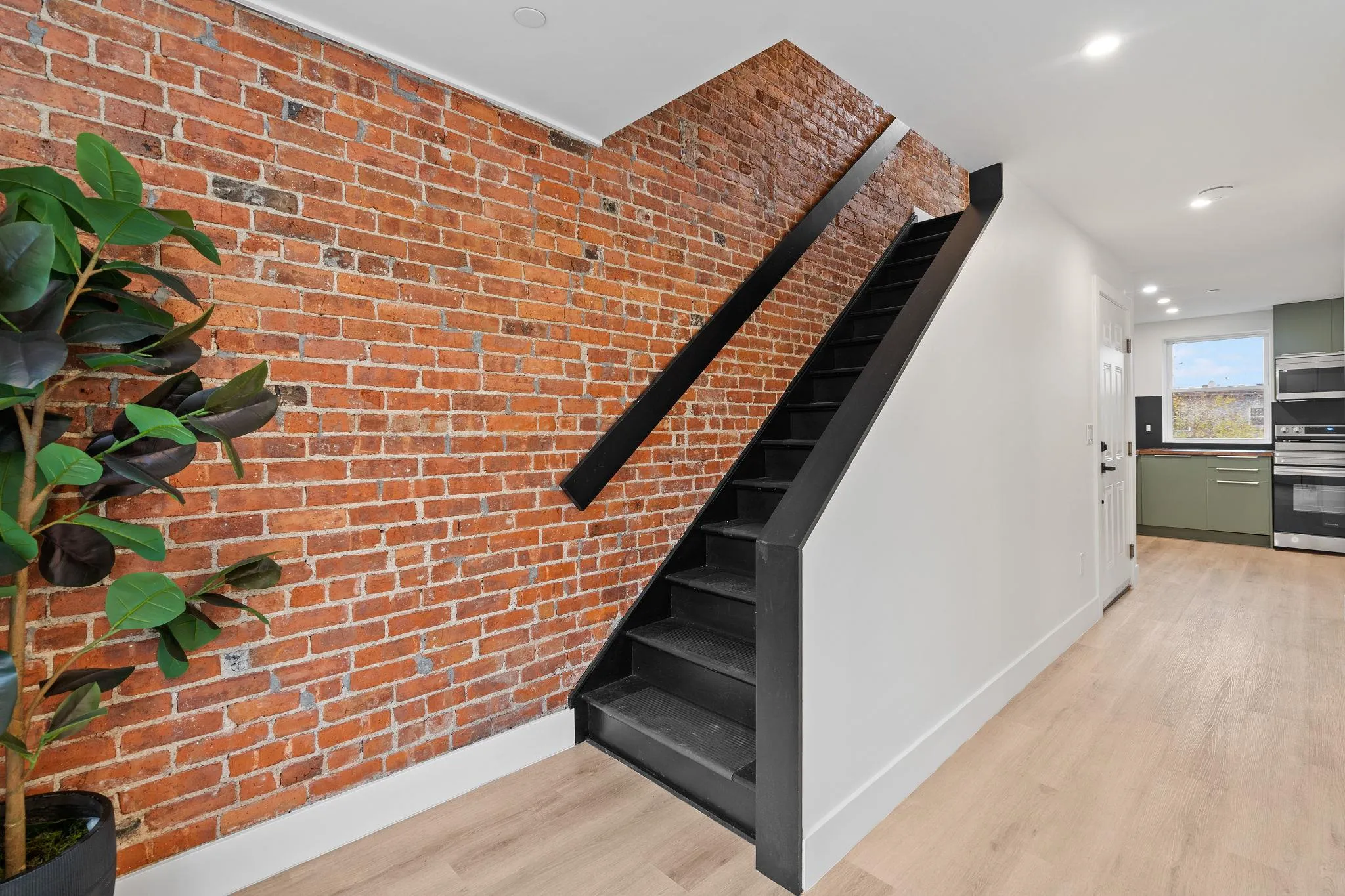 Stairs featuring hardwood / wood-style floors and brick wall Stairs featuring hardwood / wood-style floors and brick wall