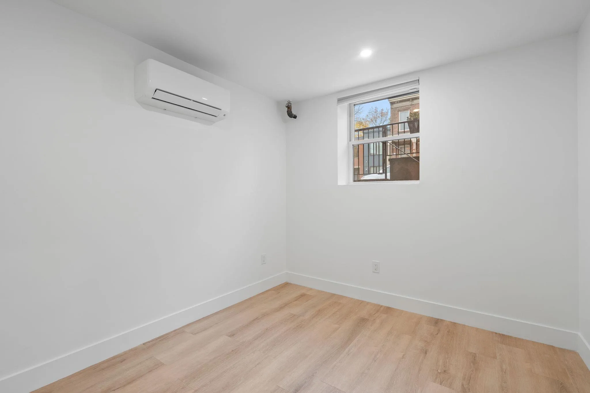 Empty room featuring a wall mounted air conditioner and light wood-type flooring Empty room featuring a wall mounted air conditioner and light wood-type flooring