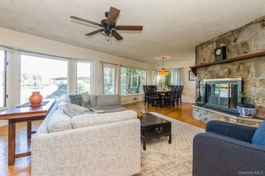 Living room featuring light wood finished floors, ceiling fan, and a fireplace Living room featuring light wood finished floors, ceiling fan, and a fireplace