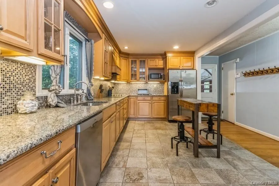Kitchen with stainless steel appliances, light stone countertops, decorative backsplash, glass insert cabinets, and recessed lighting Kitchen with stainless steel appliances, light stone countertops, decorative backsplash, glass insert cabinets, and recessed lighting