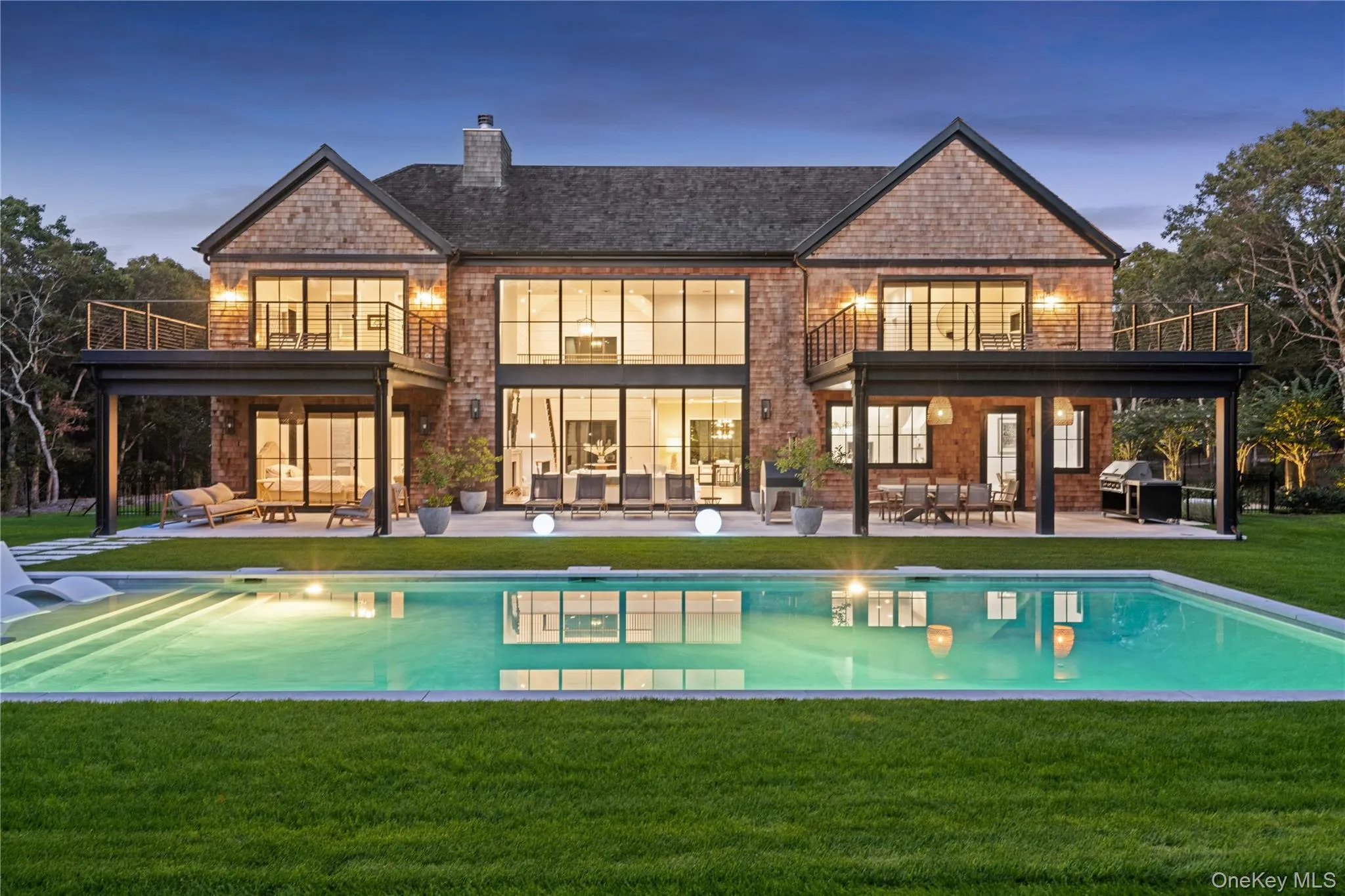Rear view of property featuring an outdoor pool, a patio, a lawn, and a balcony Rear view of property featuring an outdoor pool, a patio, a lawn, and a balcony