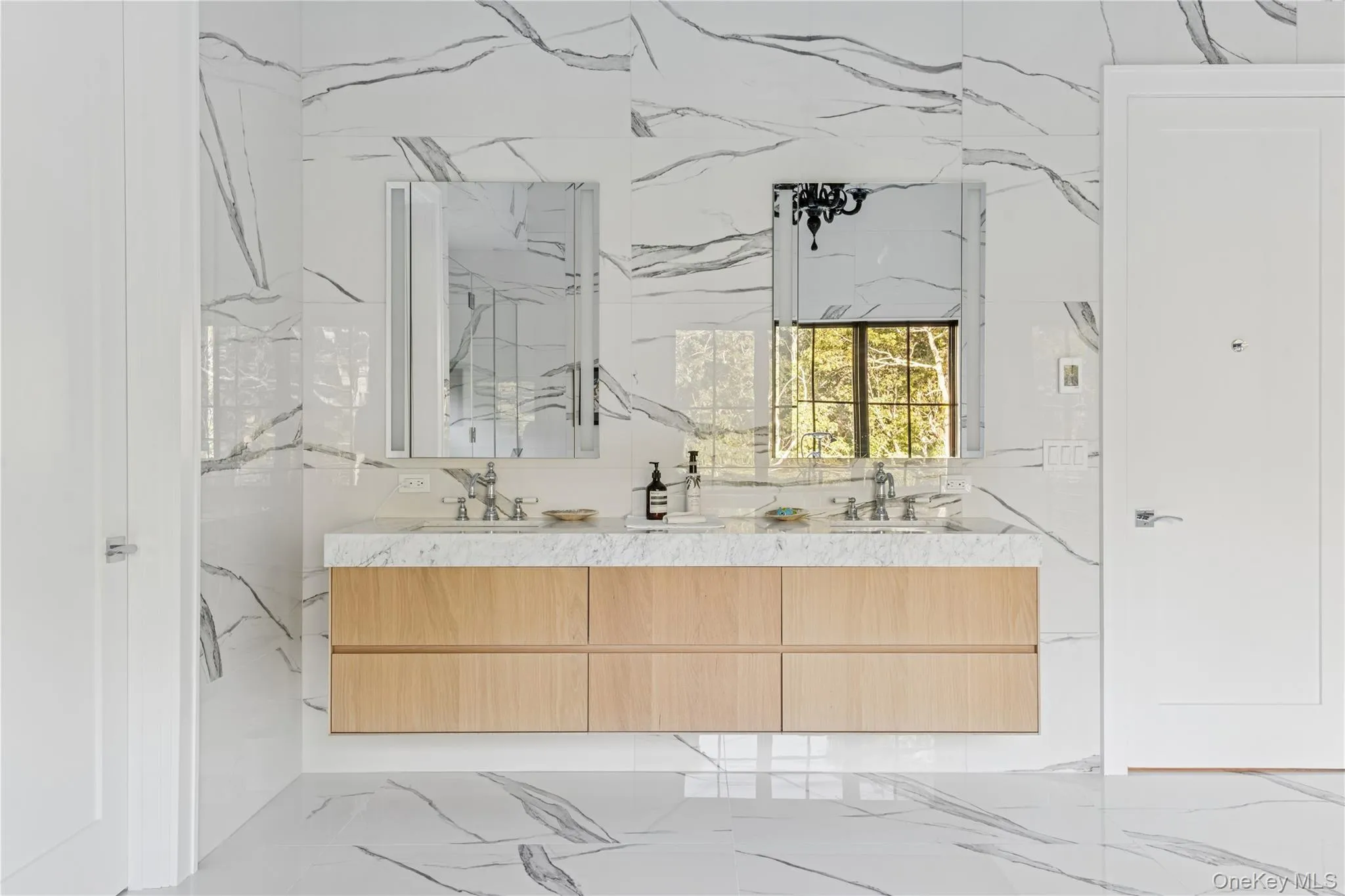 Bathroom featuring light marble finish flooring and double vanity Bathroom featuring light marble finish flooring and double vanity