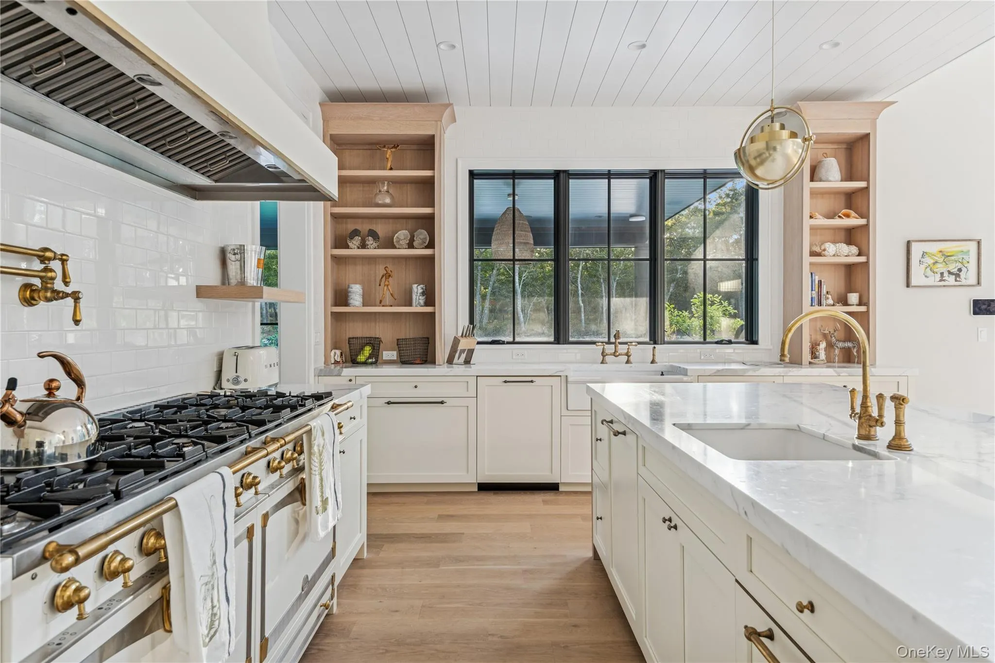 Kitchen featuring open shelves, premium range hood, high end white range, light stone countertops, and light wood-style floors Kitchen featuring open shelves, premium range hood, high end white range, light stone countertops, and light wood-style floors