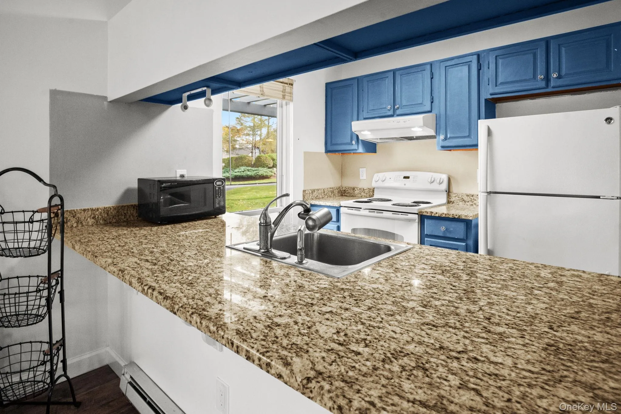 The granite kitchen offers ample counter space, stainless sink, and a bright pass-through to the dining area with garden views. The granite kitchen offers ample counter space, stainless sink, and a bright pass-through to the dining area with garden views.