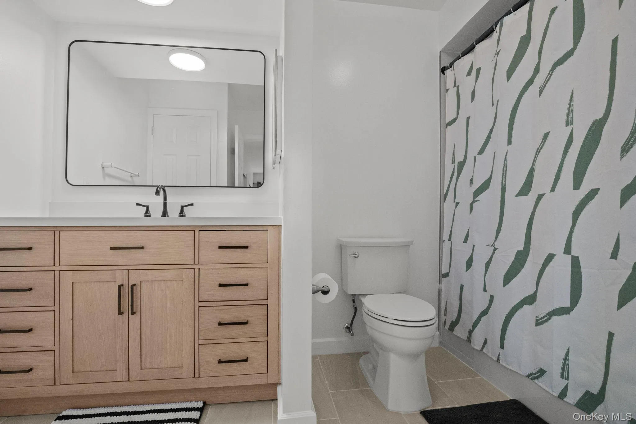 The renovated en suite bath showcases a modern wood vanity, matte black fixtures, and clean contemporary design. The renovated en suite bath showcases a modern wood vanity, matte black fixtures, and clean contemporary design.
