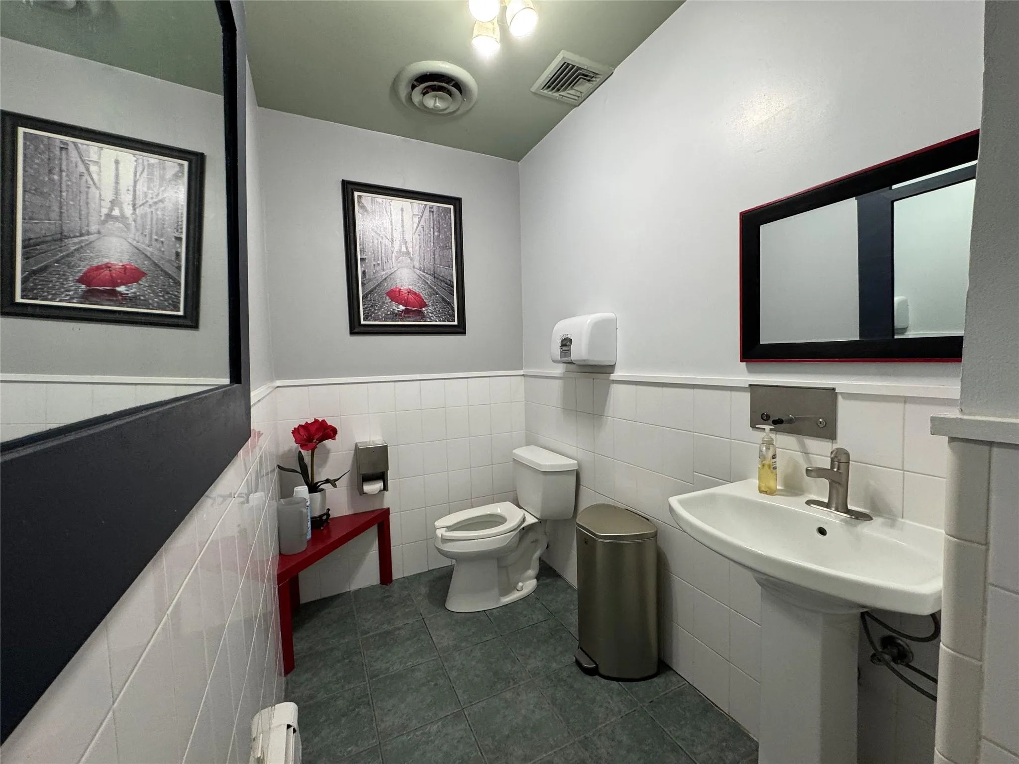 Half bathroom with tile patterned floors, wainscoting, tile walls, and a baseboard heating unit Half bathroom with tile patterned floors, wainscoting, tile walls, and a baseboard heating unit