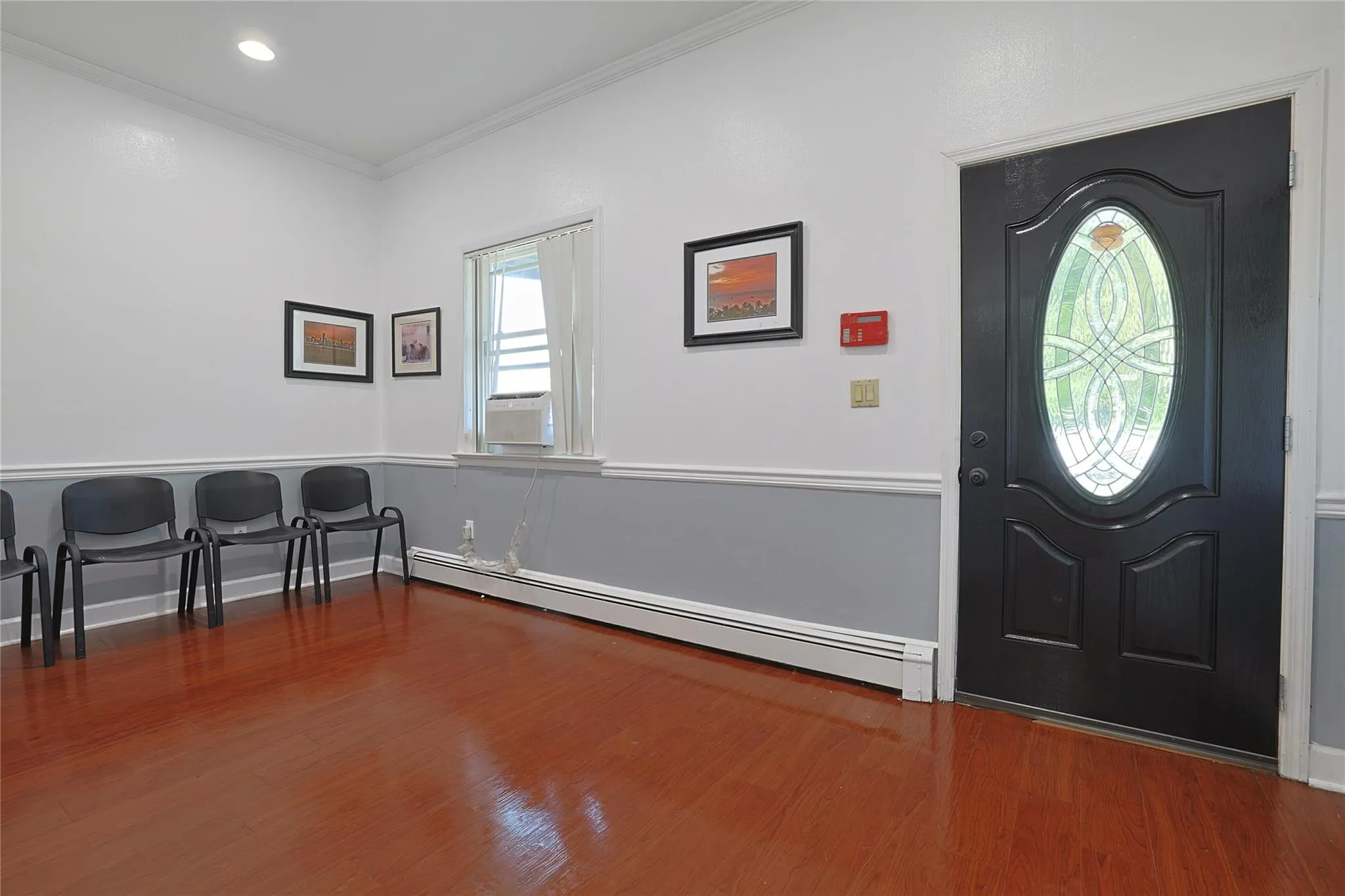 Entrance foyer with a baseboard radiator, wood finished floors, crown molding, and cooling unit Entrance foyer with a baseboard radiator, wood finished floors, crown molding, and cooling unit