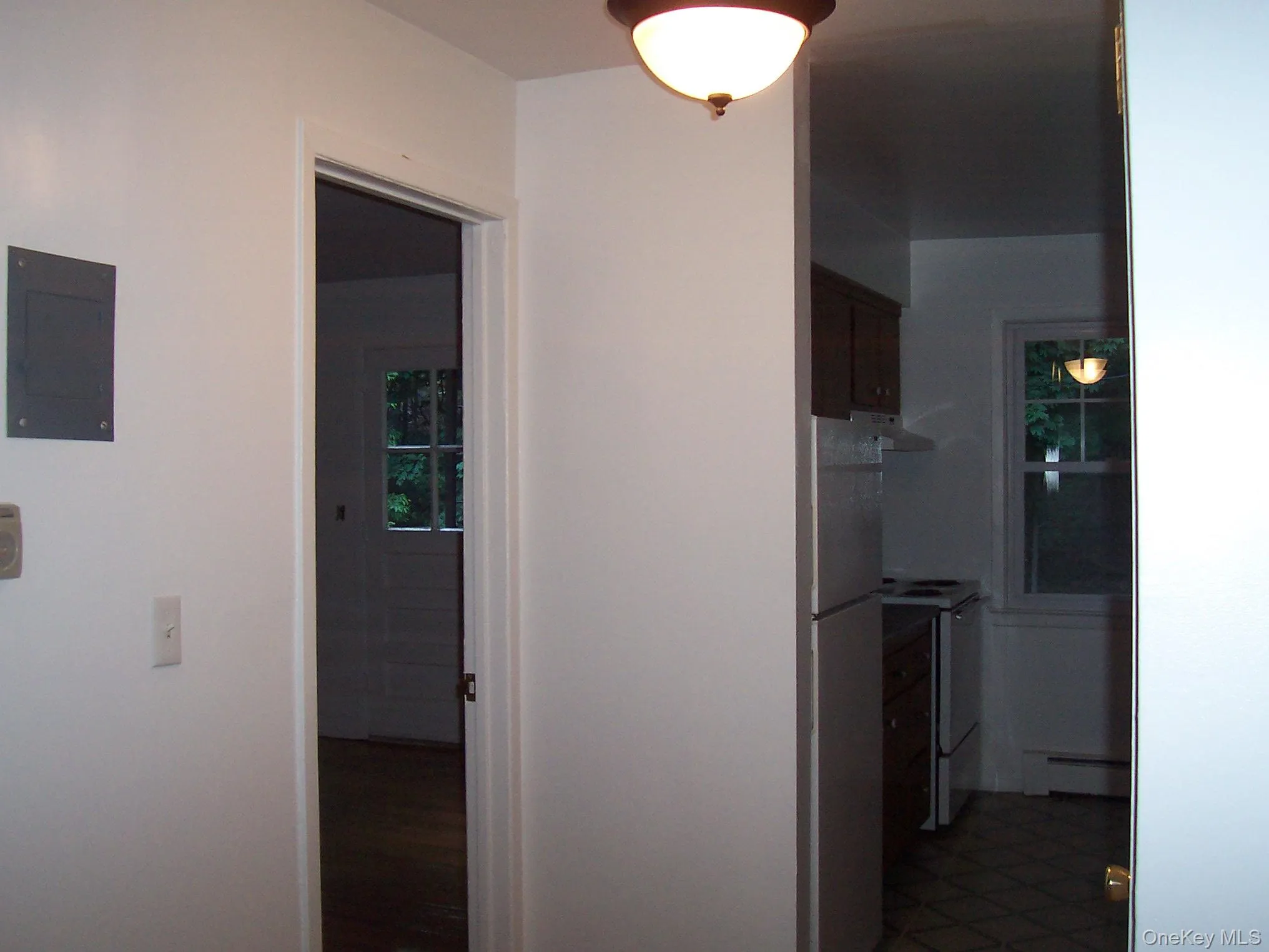 Hall featuring baseboard heating, electric panel, and dark tile patterned floors Hall featuring baseboard heating, electric panel, and dark tile patterned floors
