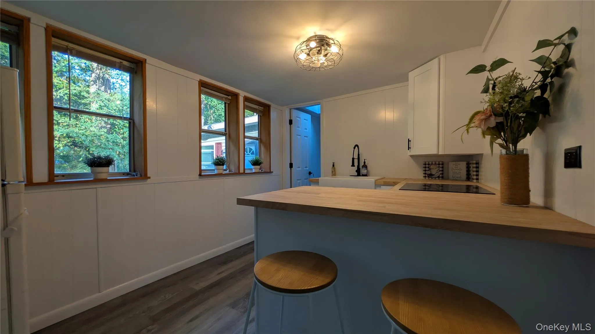 Kitchen with a peninsula, white cabinets, wooden counters, dark wood-type flooring, and a kitchen breakfast bar Kitchen with a peninsula, white cabinets, wooden counters, dark wood-type flooring, and a kitchen breakfast bar