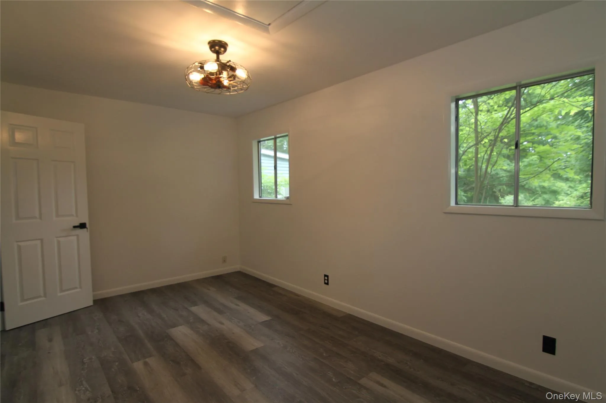 Spare room featuring baseboards and dark wood-style floors Spare room featuring baseboards and dark wood-style floors