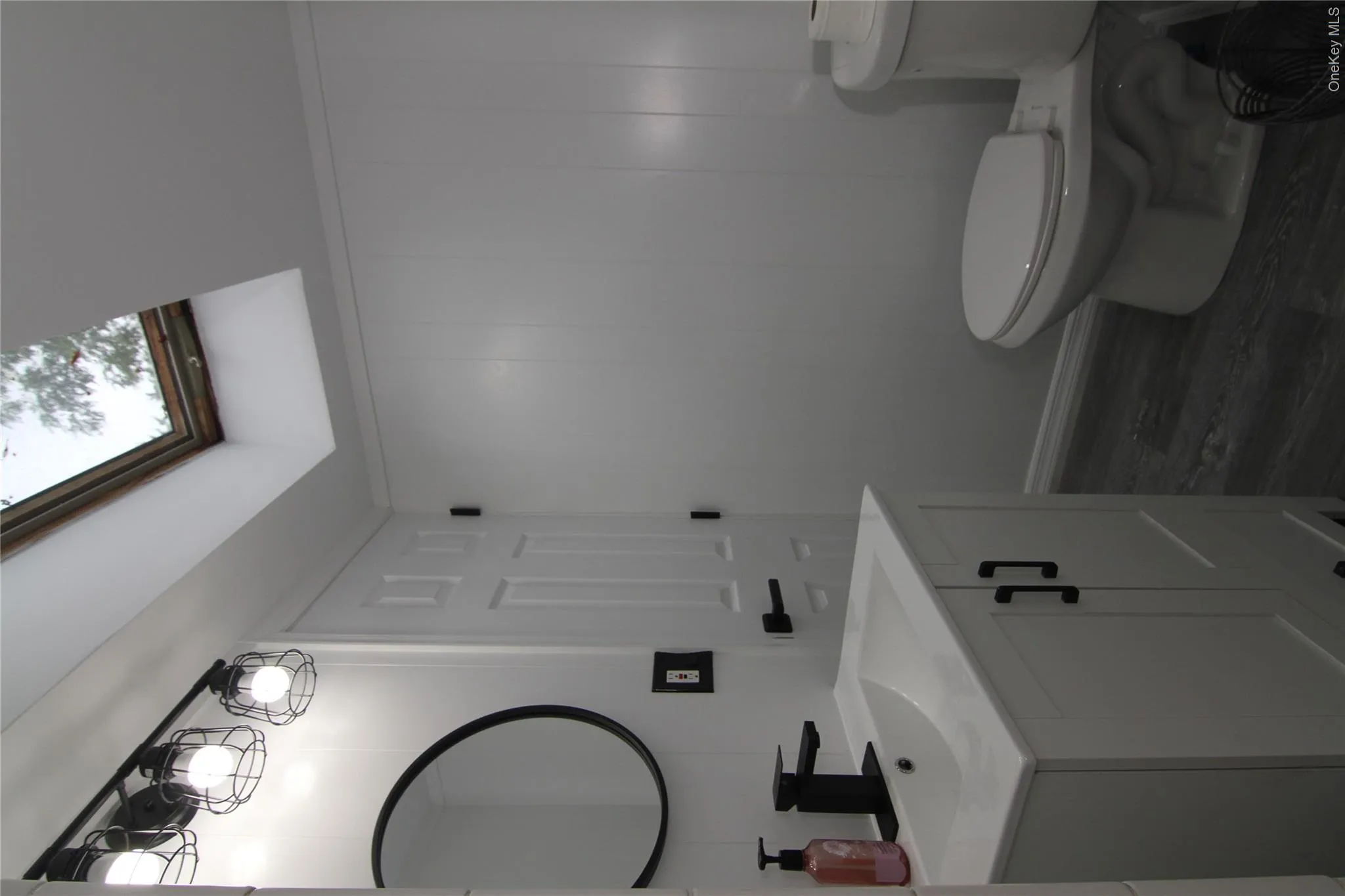 Bathroom with vanity, a skylight, wood finished floors, and a decorative wall Bathroom with vanity, a skylight, wood finished floors, and a decorative wall