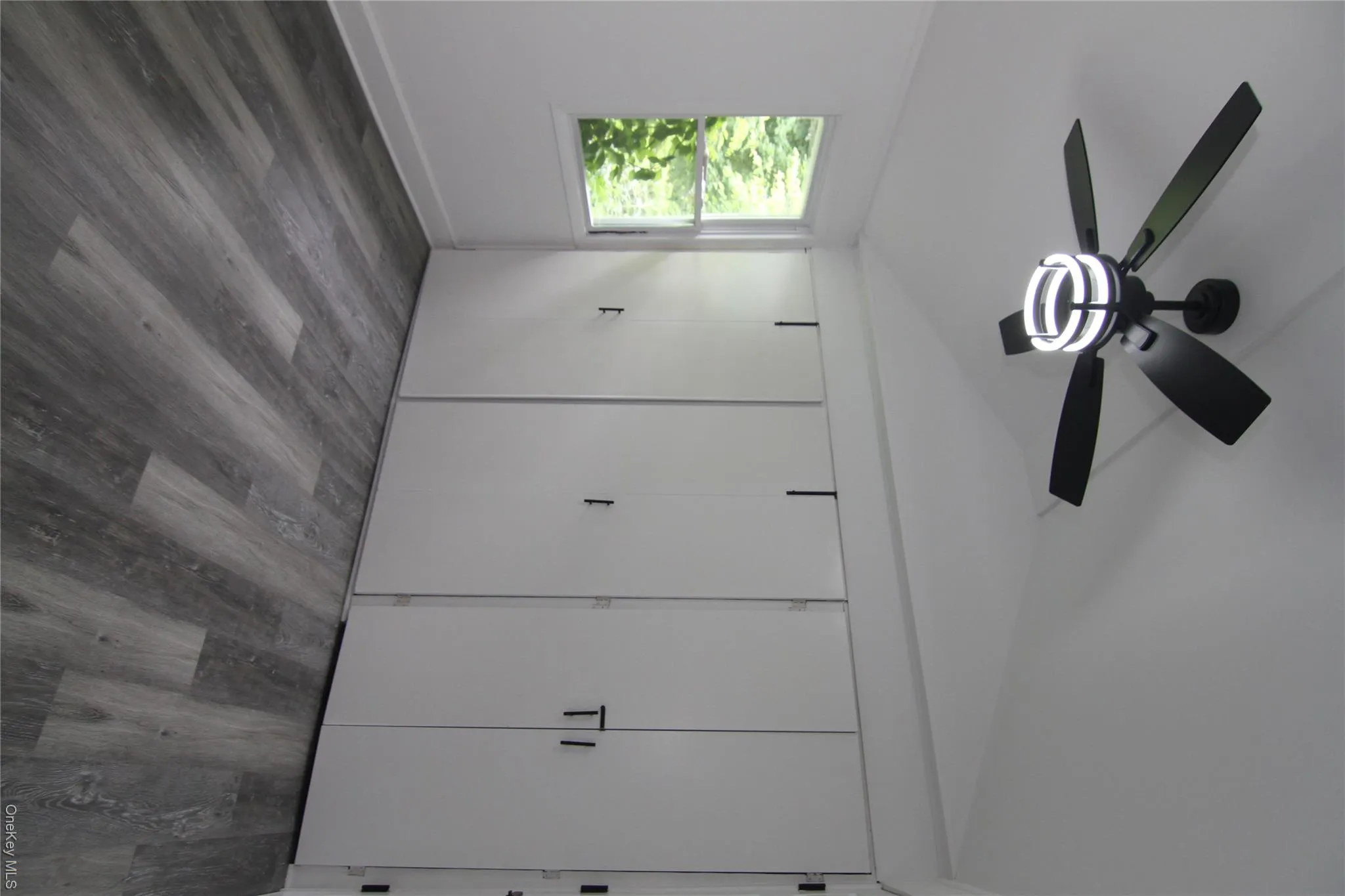 Unfurnished bedroom with lofted ceiling, wood finished floors, and a ceiling fan Unfurnished bedroom with lofted ceiling, wood finished floors, and a ceiling fan