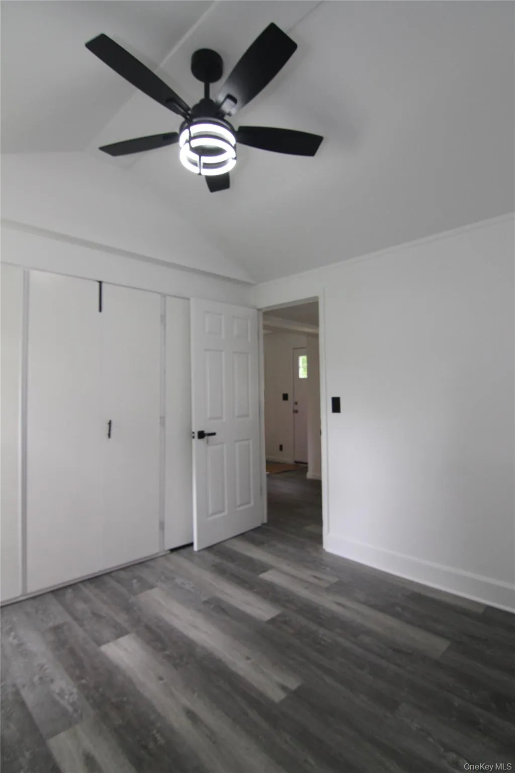Unfurnished bedroom with lofted ceiling, dark wood finished floors, ceiling fan, and a closet Unfurnished bedroom with lofted ceiling, dark wood finished floors, ceiling fan, and a closet