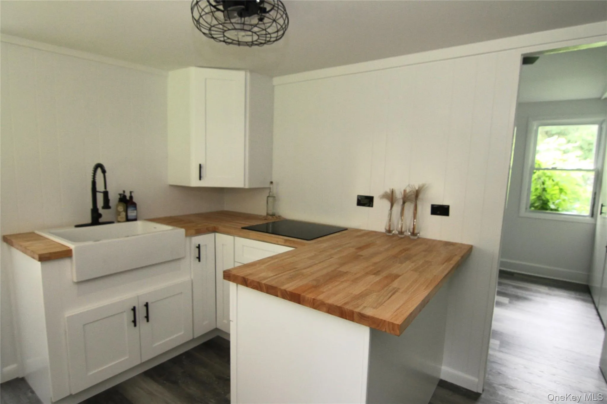 Kitchen with butcher block countertops, black electric cooktop, dark wood-style floors, and white cabinets Kitchen with butcher block countertops, black electric cooktop, dark wood-style floors, and white cabinets