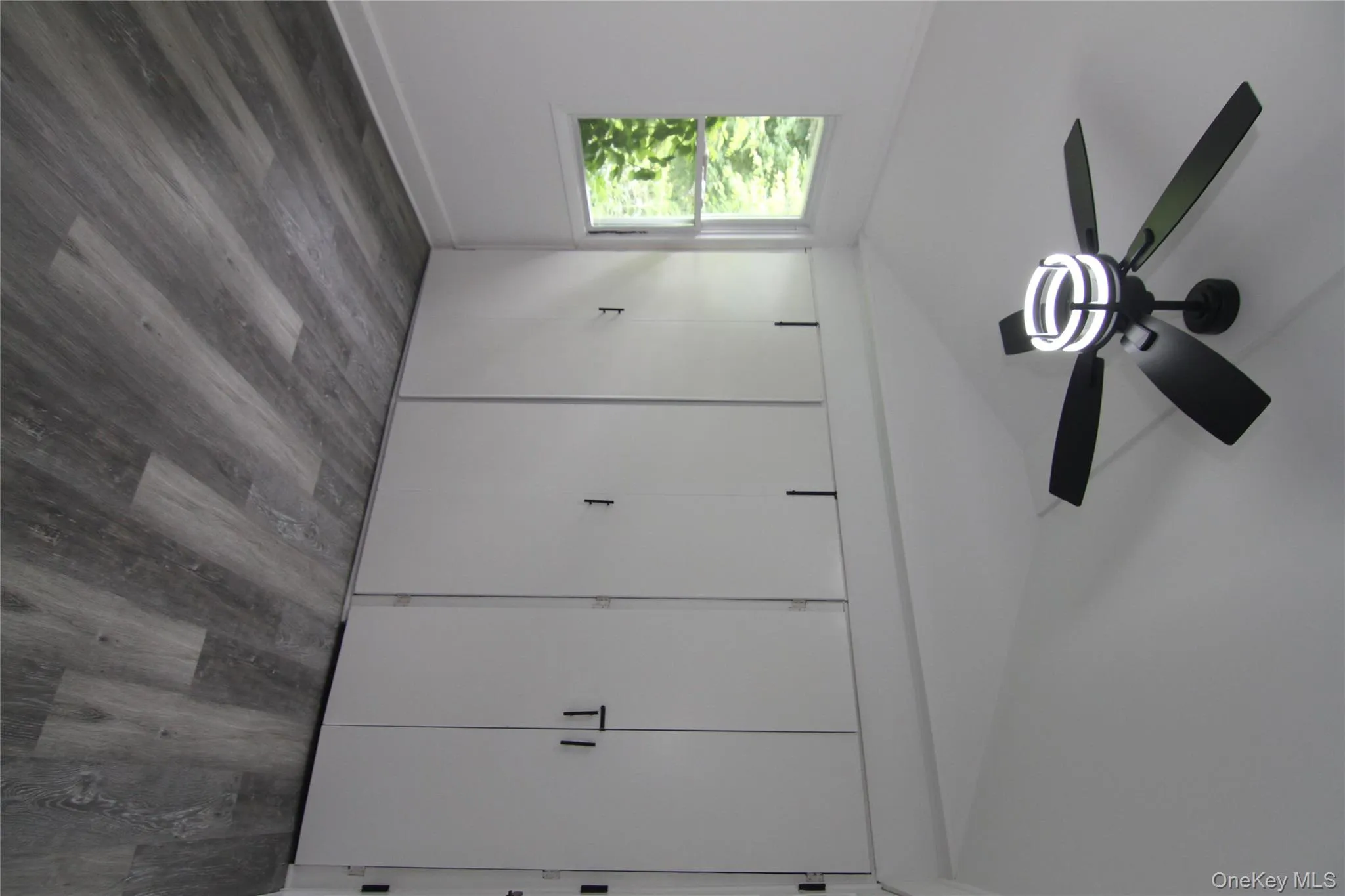 Unfurnished bedroom with lofted ceiling, wood finished floors, and a ceiling fan Unfurnished bedroom with lofted ceiling, wood finished floors, and a ceiling fan