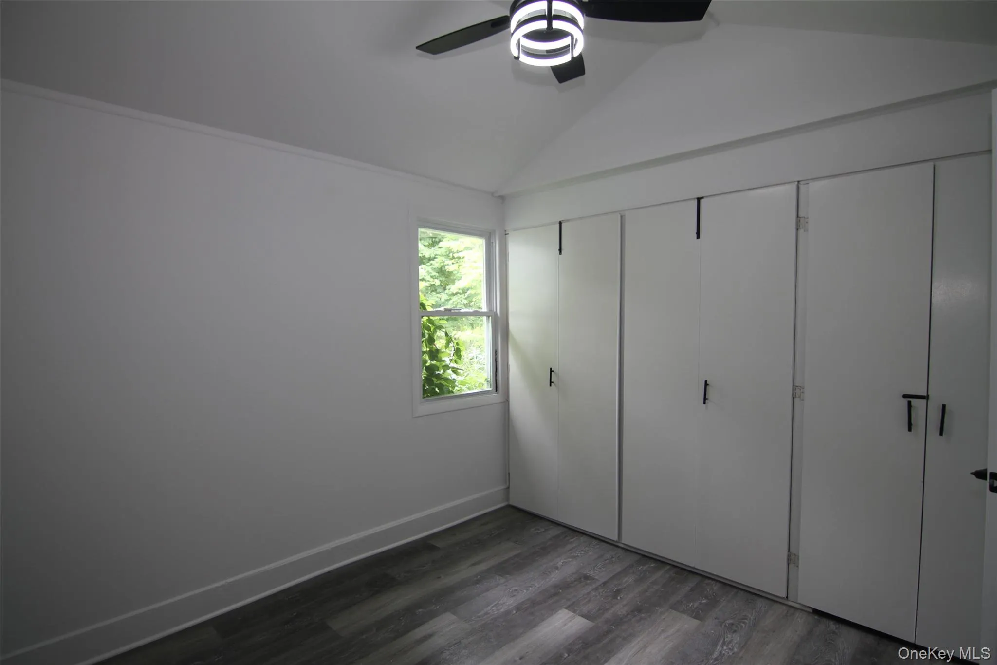Unfurnished bedroom with dark wood finished floors, lofted ceiling, a ceiling fan, and a closet Unfurnished bedroom with dark wood finished floors, lofted ceiling, a ceiling fan, and a closet