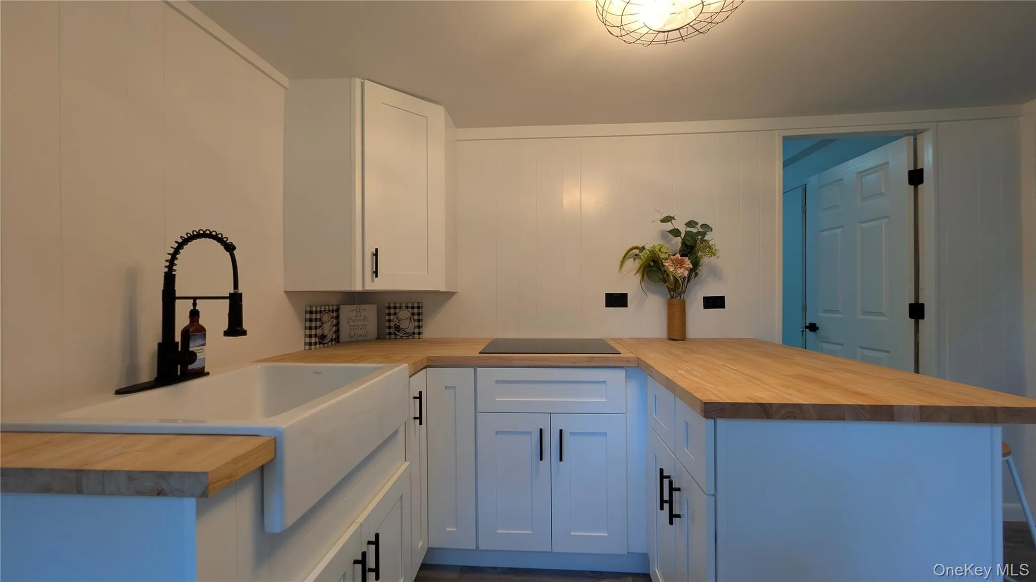 Kitchen with a peninsula, white cabinets, and black electric cooktop Kitchen with a peninsula, white cabinets, and black electric cooktop