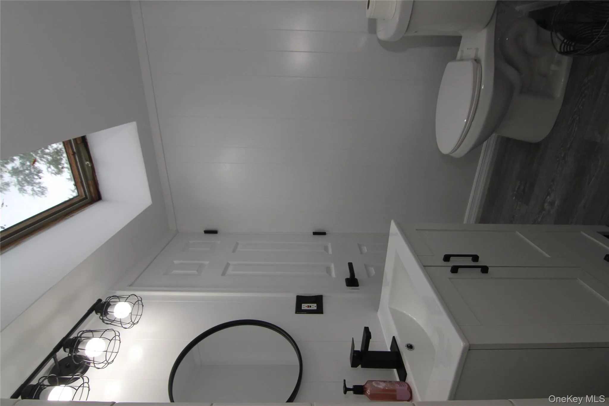 Bathroom with vanity, a skylight, wood finished floors, and a decorative wall Bathroom with vanity, a skylight, wood finished floors, and a decorative wall