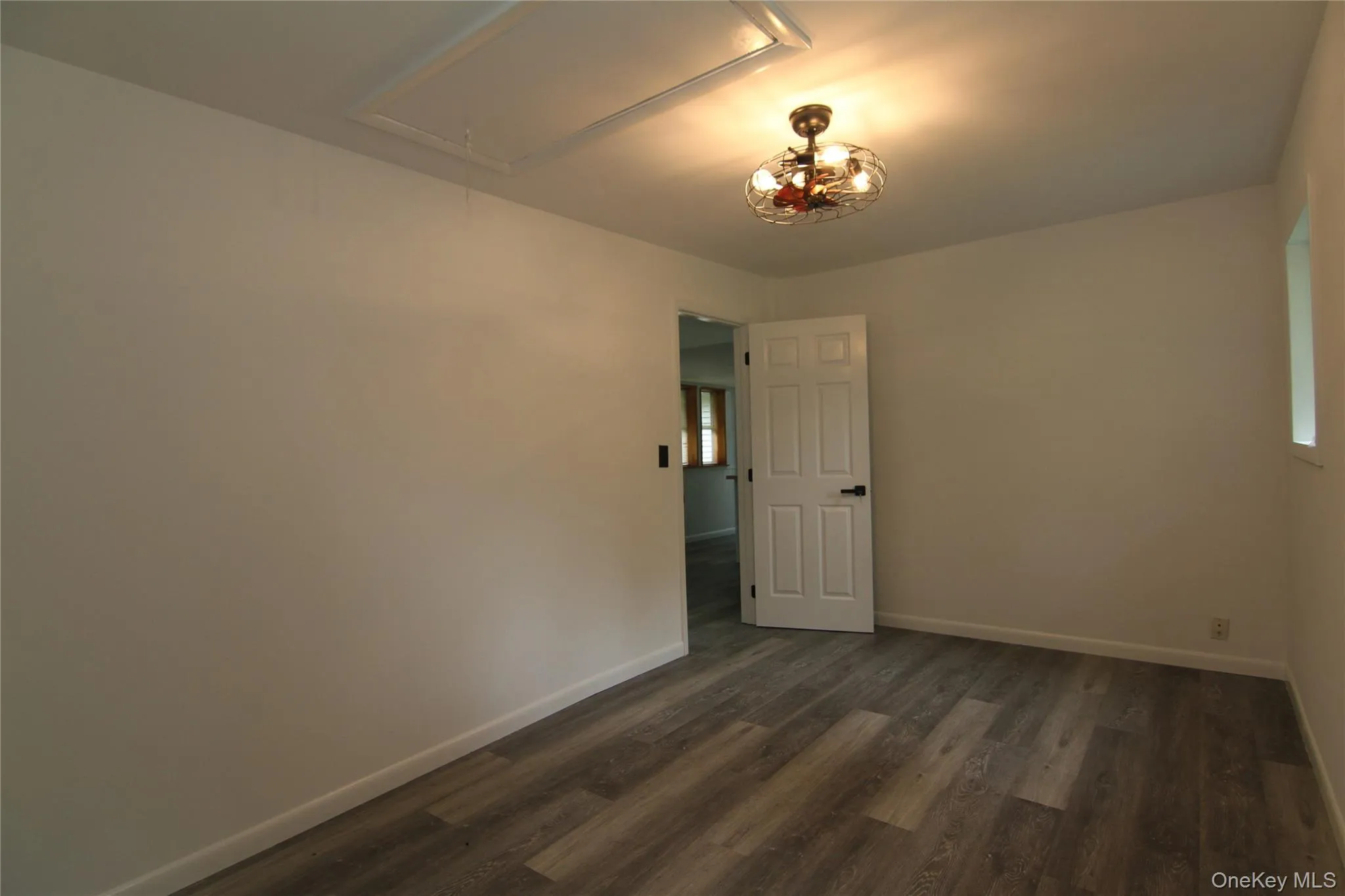 Empty room with attic access and dark wood-style flooring Empty room with attic access and dark wood-style flooring