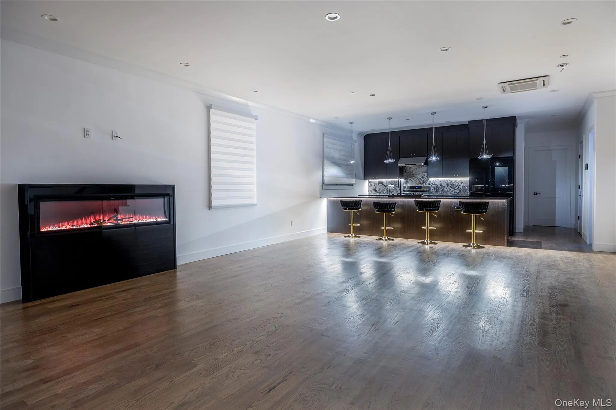 Living room featuring dark wood-style floors, a glass covered fireplace, and recessed lighting Living room featuring dark wood-style floors, a glass covered fireplace, and recessed lighting