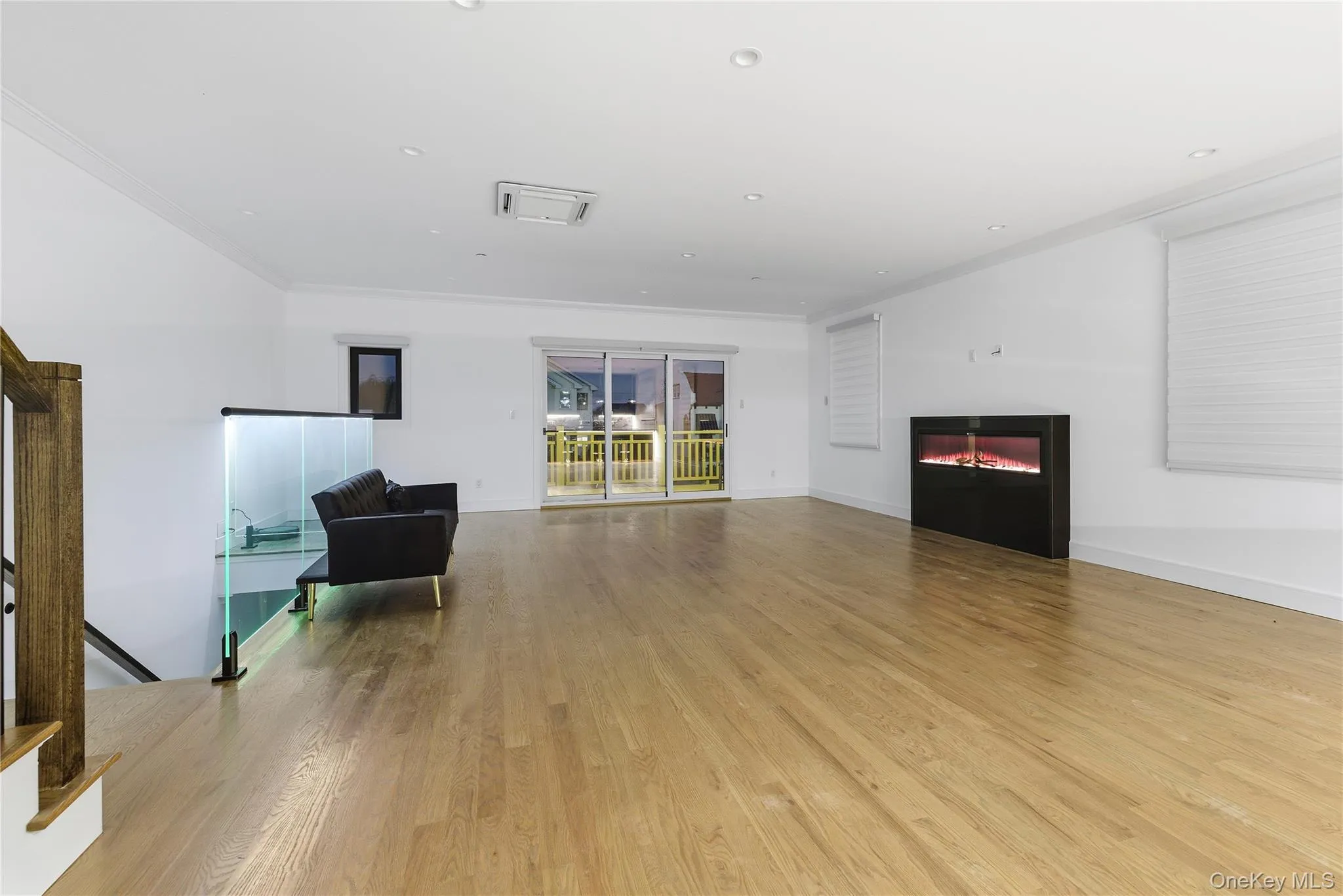 Living room with light wood-style flooring, recessed lighting, a glass covered fireplace, and crown molding Living room with light wood-style flooring, recessed lighting, a glass covered fireplace, and crown molding