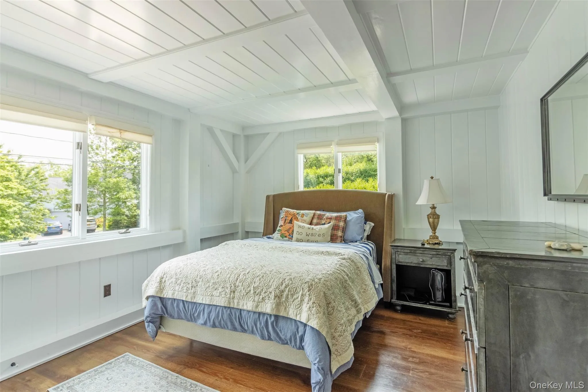Bedroom featuring dark wood-style flooring, beamed ceiling, and wooden walls Bedroom featuring dark wood-style flooring, beamed ceiling, and wooden walls