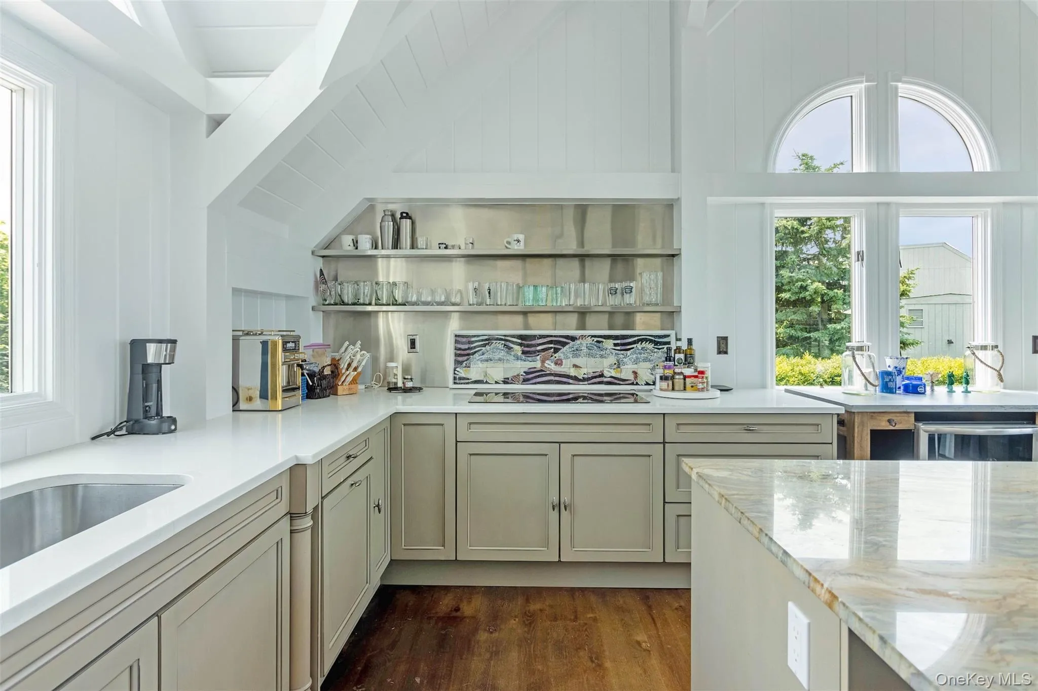 Kitchen featuring plenty of natural light, dark wood finished floors, vaulted ceiling, light stone counters, and white stovetop Kitchen featuring plenty of natural light, dark wood finished floors, vaulted ceiling, light stone counters, and white stovetop