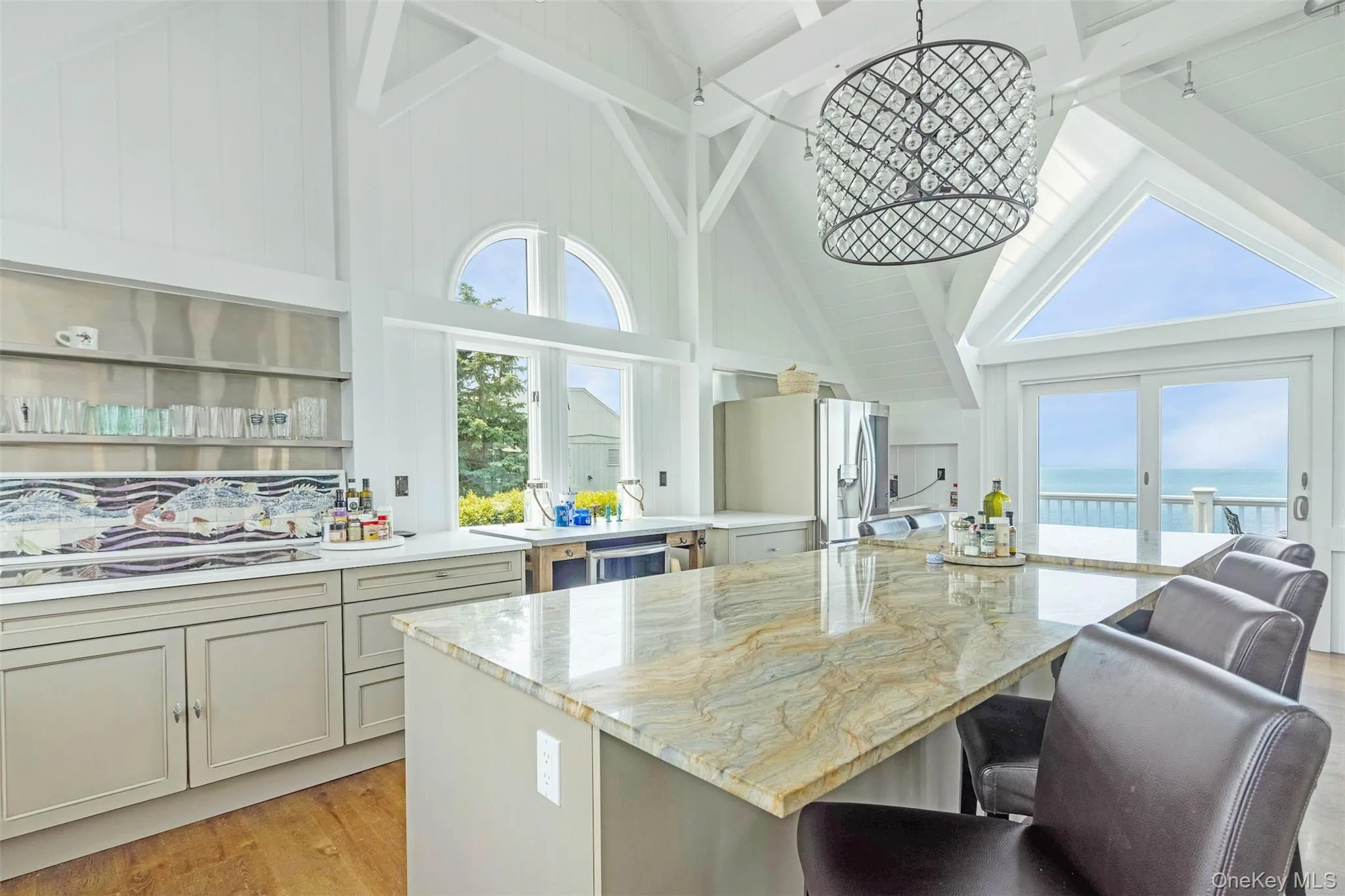 Kitchen featuring high vaulted ceiling, stainless steel fridge, a kitchen breakfast bar, plenty of natural light, and a water view Kitchen featuring high vaulted ceiling, stainless steel fridge, a kitchen breakfast bar, plenty of natural light, and a water view