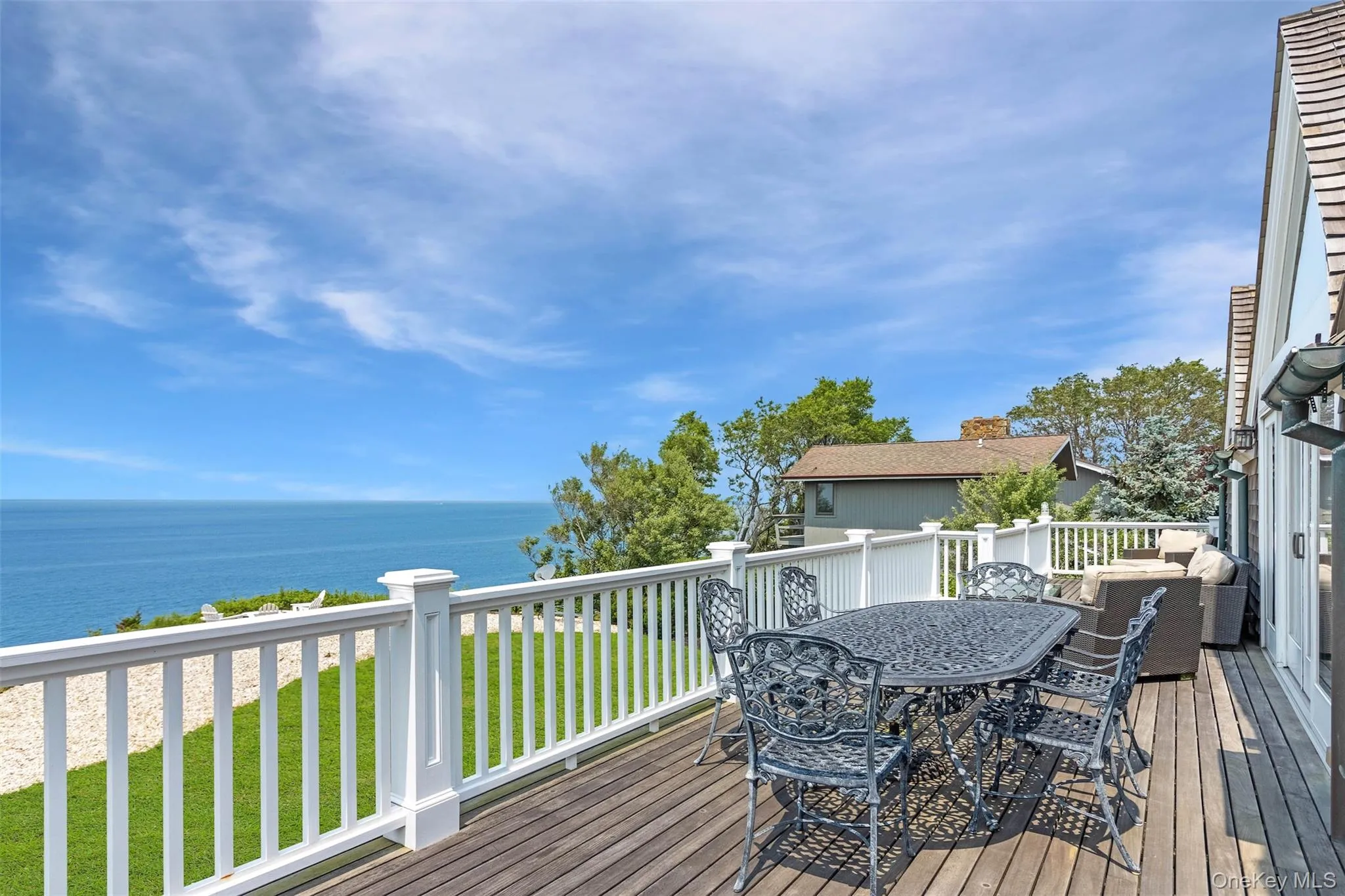 Wooden deck featuring outdoor dining space, a water view, and a lawn Wooden deck featuring outdoor dining space, a water view, and a lawn