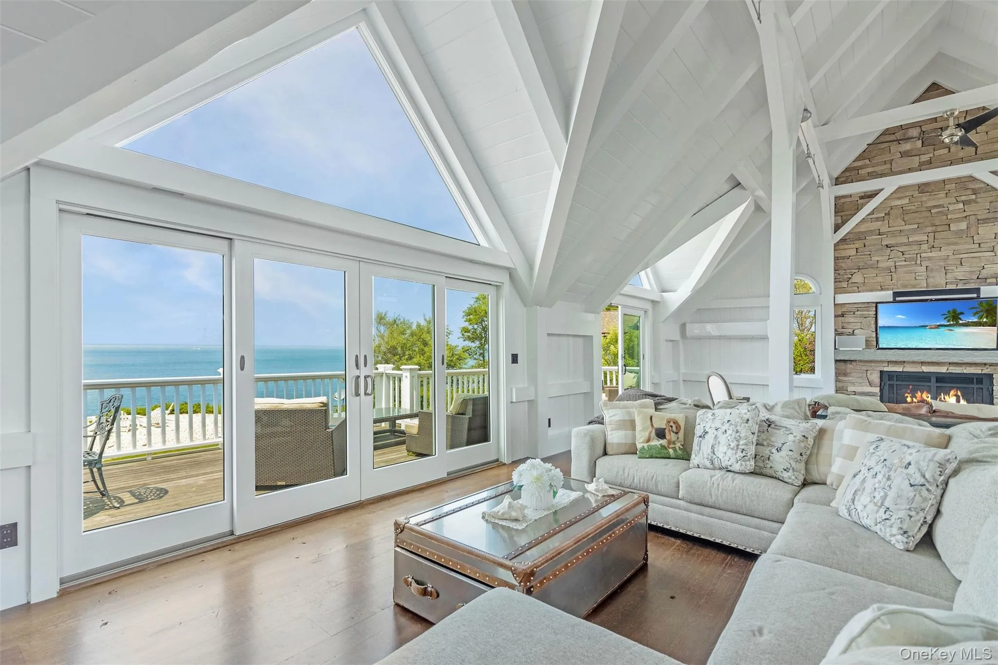 Living area featuring beamed ceiling, a water view, a fireplace, wood finished floors, and high vaulted ceiling Living area featuring beamed ceiling, a water view, a fireplace, wood finished floors, and high vaulted ceiling