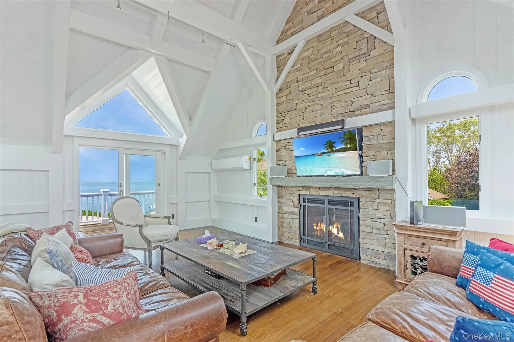 Living area with a fireplace, wood finished floors, high vaulted ceiling, beam ceiling, and plenty of natural light Living area with a fireplace, wood finished floors, high vaulted ceiling, beam ceiling, and plenty of natural light