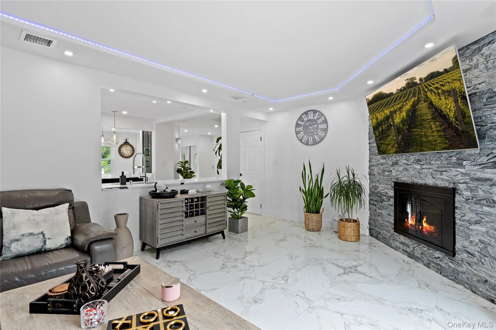 Living room featuring recessed lighting, a fireplace, a raised ceiling, and marble tiled floors Living room featuring recessed lighting, a fireplace, a raised ceiling, and marble tiled floors