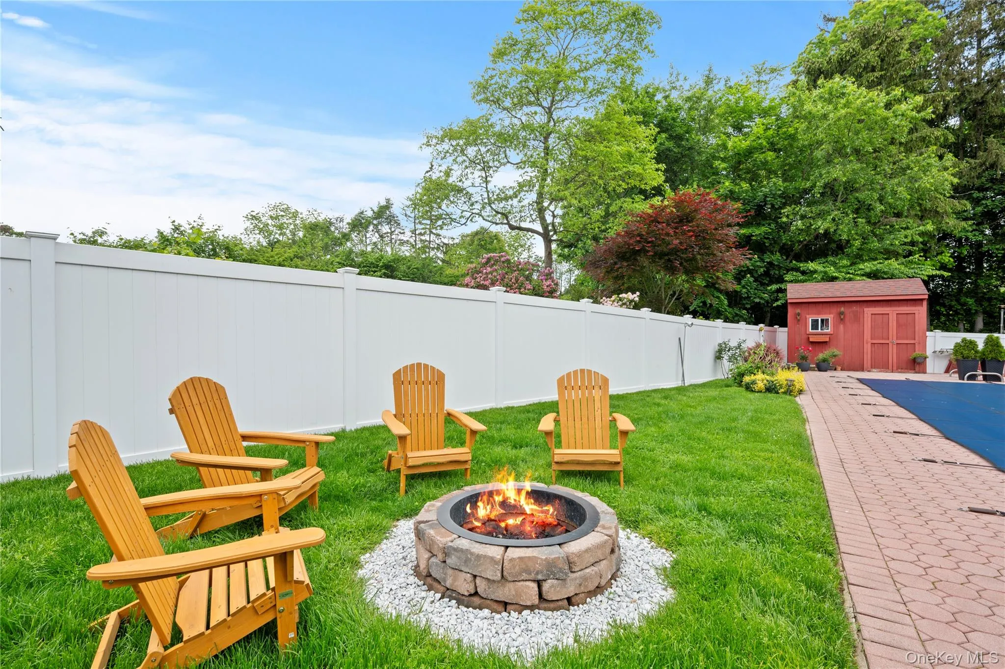 Fenced backyard with a fire pit and a storage unit Fenced backyard with a fire pit and a storage unit