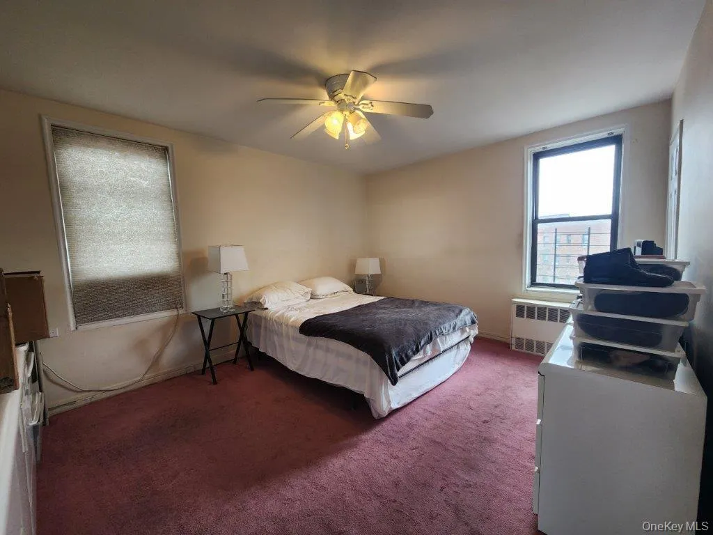 Carpeted bedroom with radiator heating unit and ceiling fan Carpeted bedroom with radiator heating unit and ceiling fan