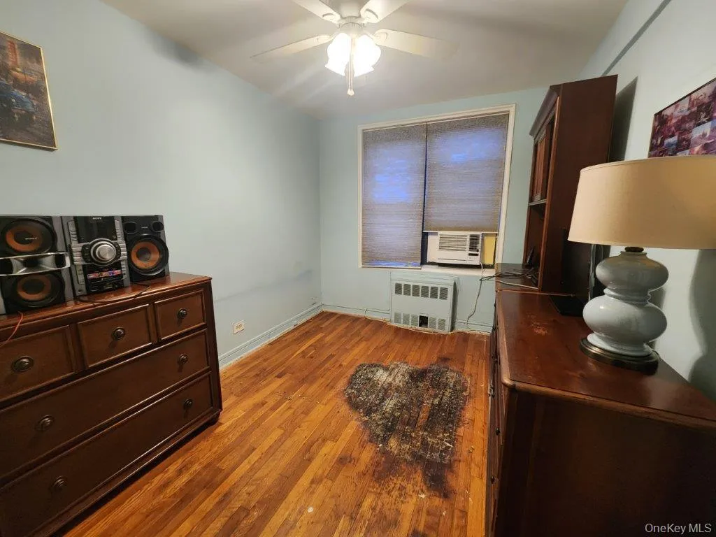 Office space featuring radiator, cooling unit, a ceiling fan, and wood finished floors Office space featuring radiator, cooling unit, a ceiling fan, and wood finished floors